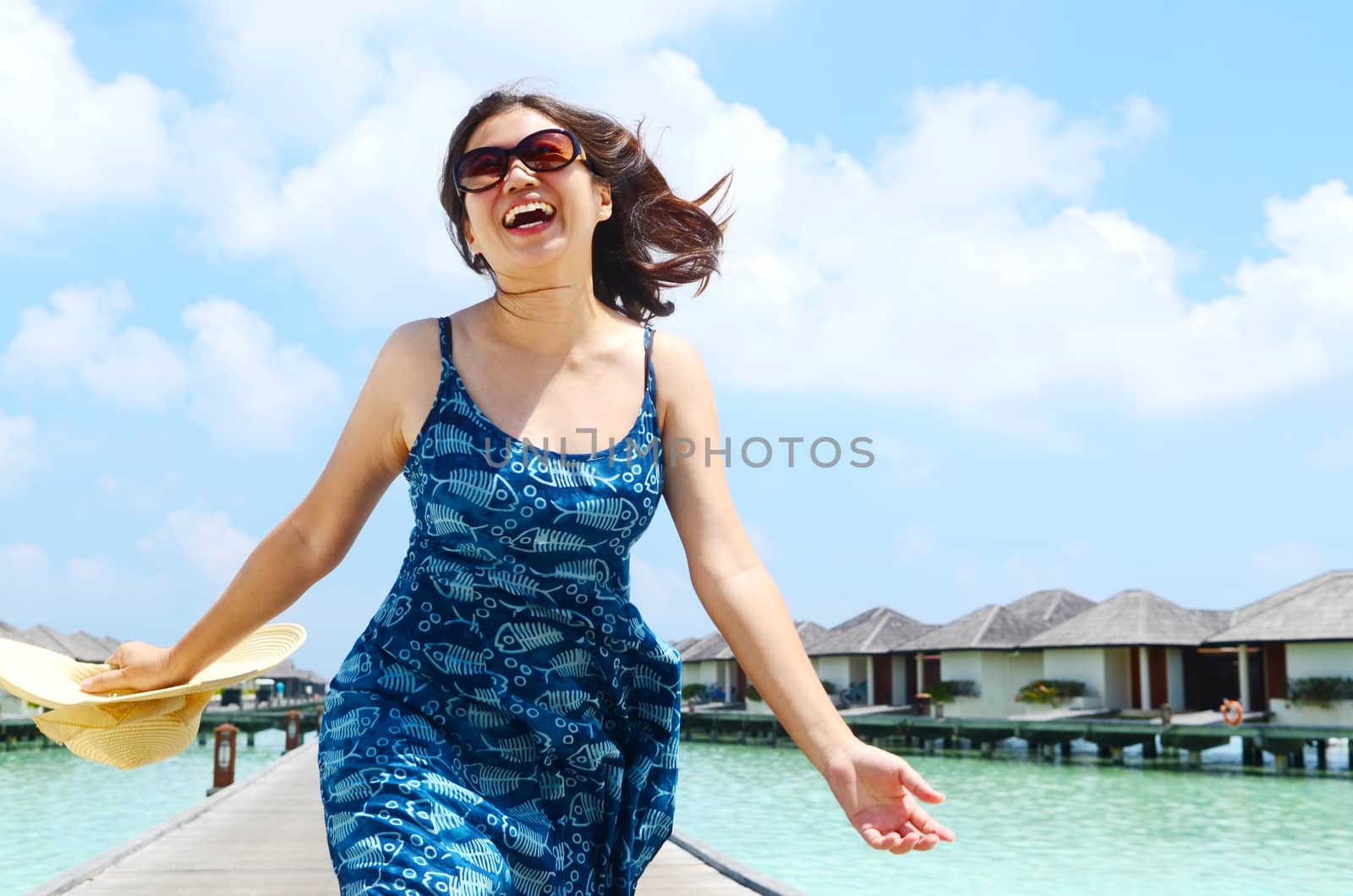 close-up portrait of a beautiful young asian girl with long hair on a background of blue sea and sky with clouds on a sunny day, lifestyle, posing and smiling.