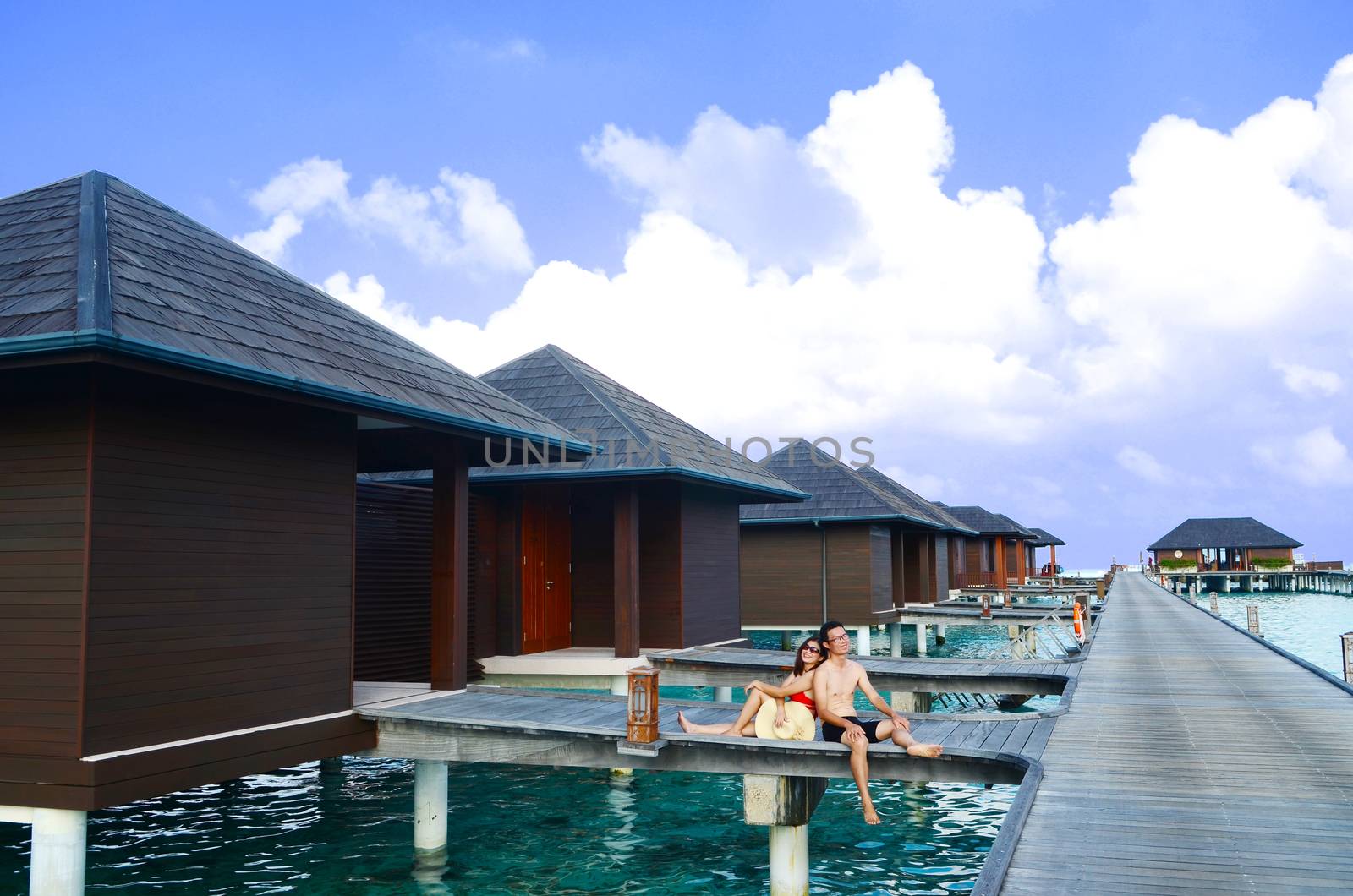 Asian couple on a tropical beach jetty at villa water resort,Maldives