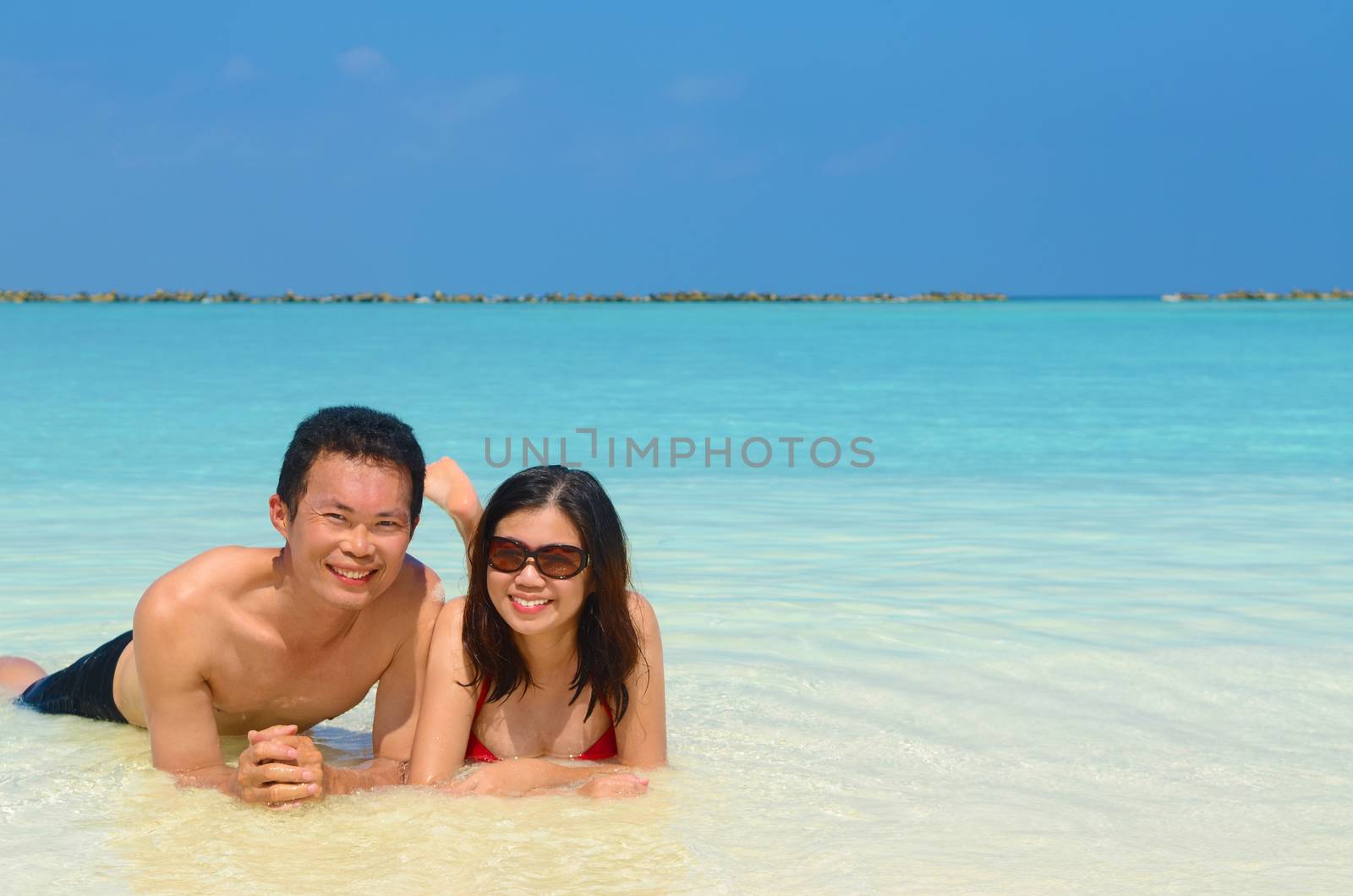 Young happy asian couple  in clean water at summer vacation in Maldives island