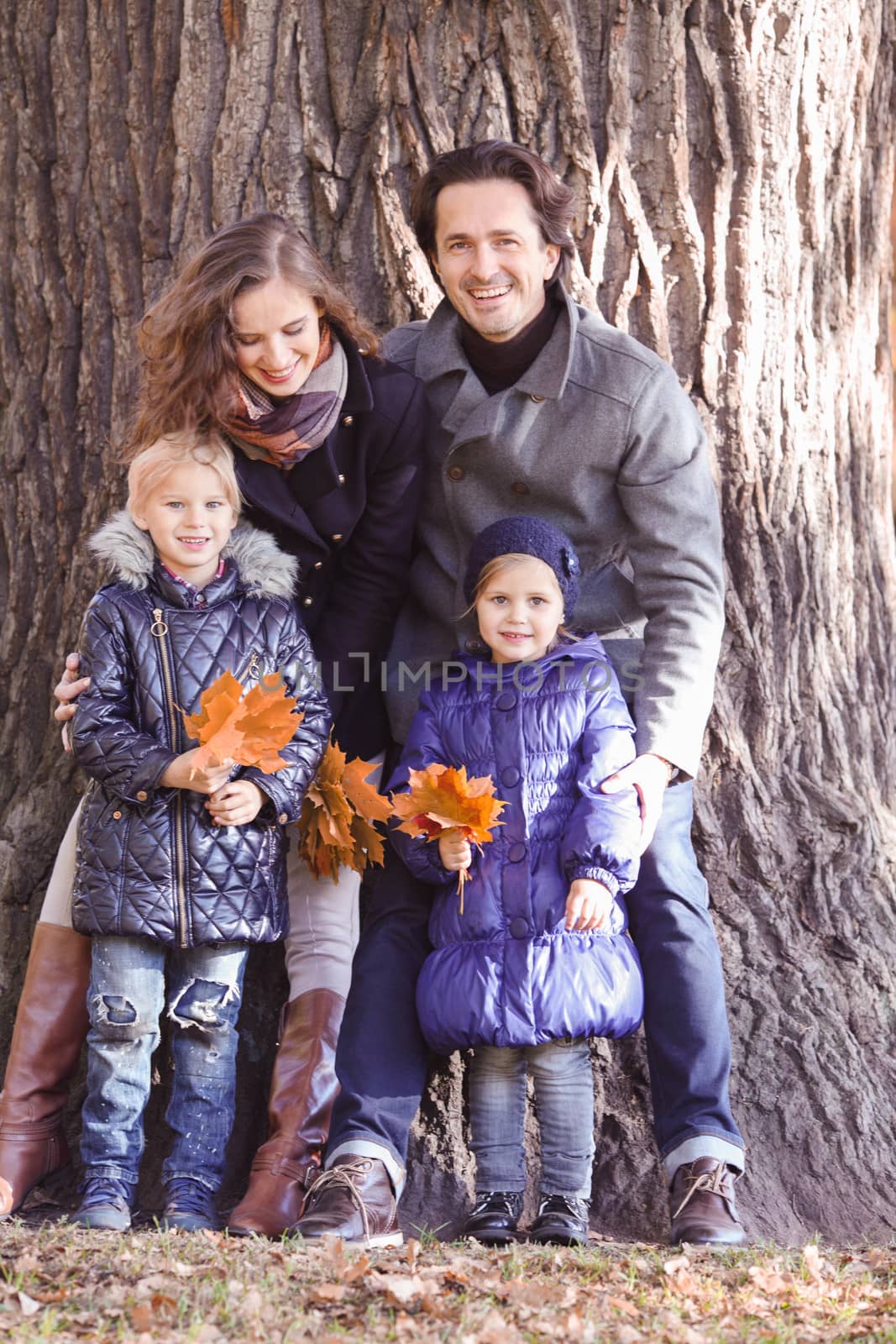 Happy smiling family of parents and children in autumn park