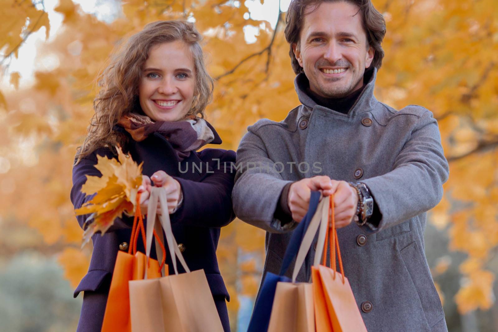 Couple with shopping paper bags in fall forest , autumn sale concept