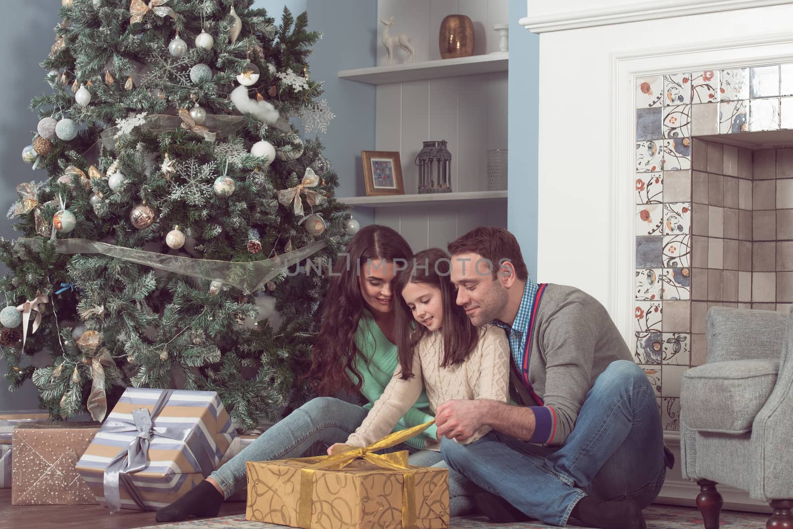 Happy family gather near Christmas tree with presents