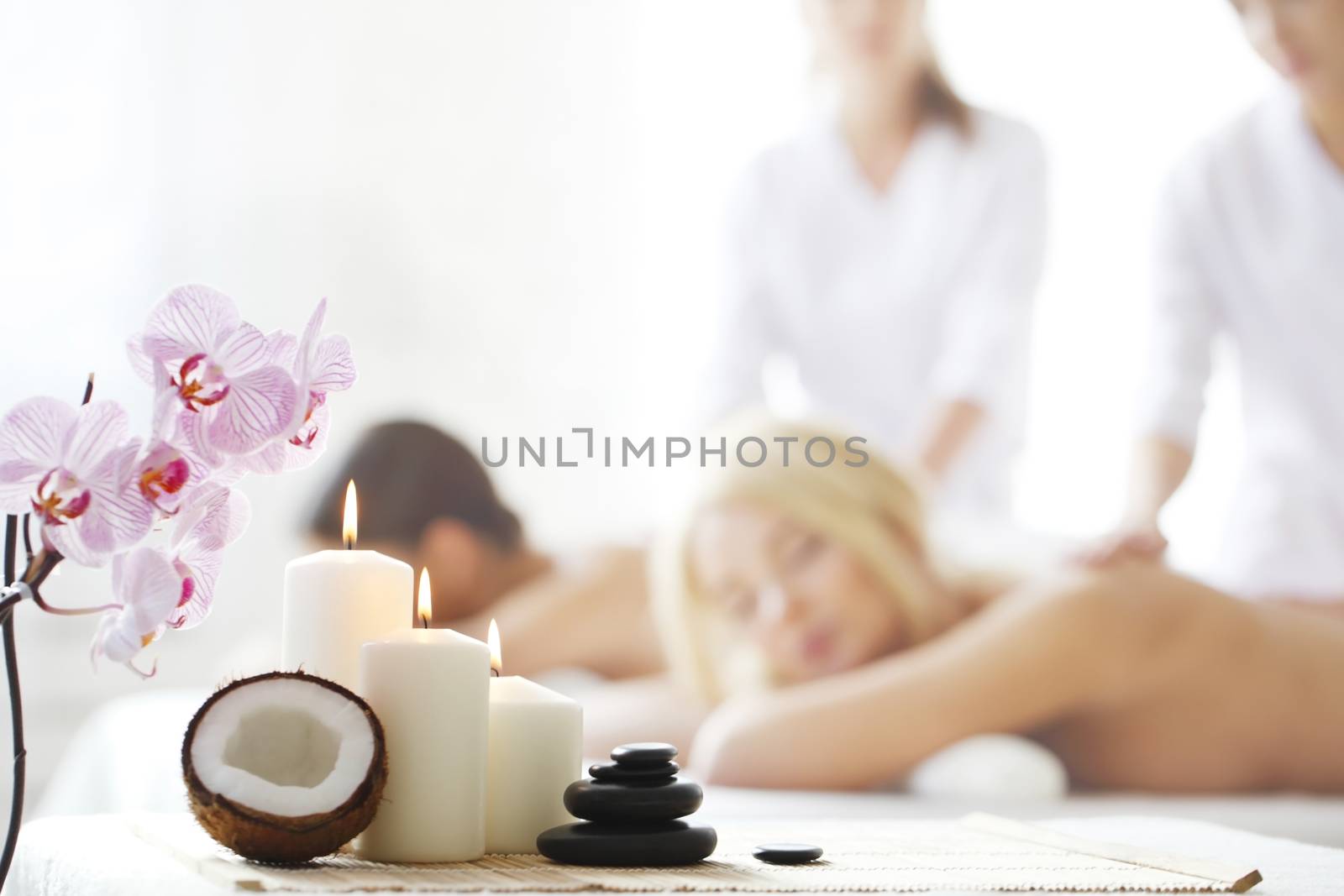 Spa massage tools and women getting massage on background