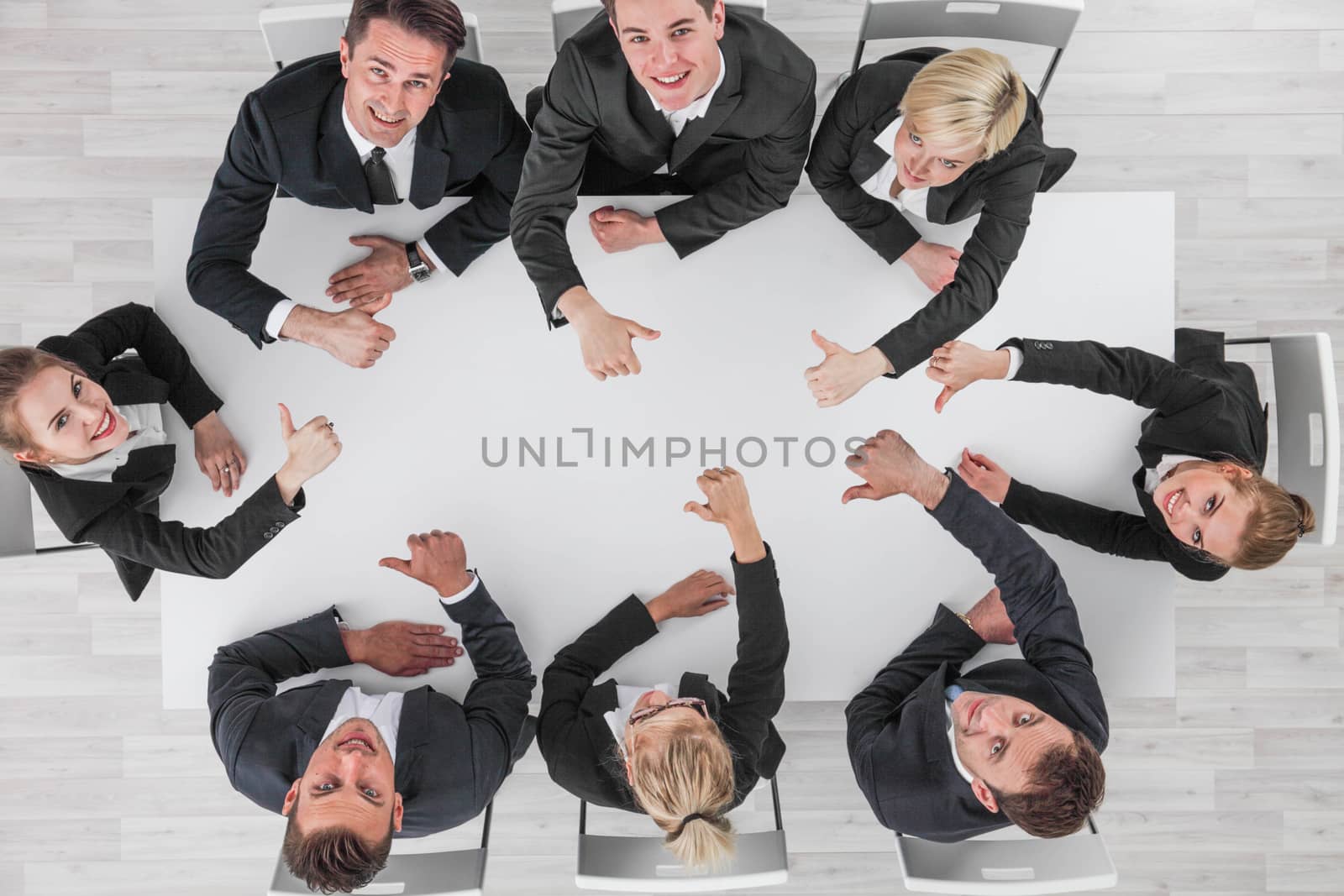 Diverse business people sitting around the table on a meeting and smiling showing thumbs up