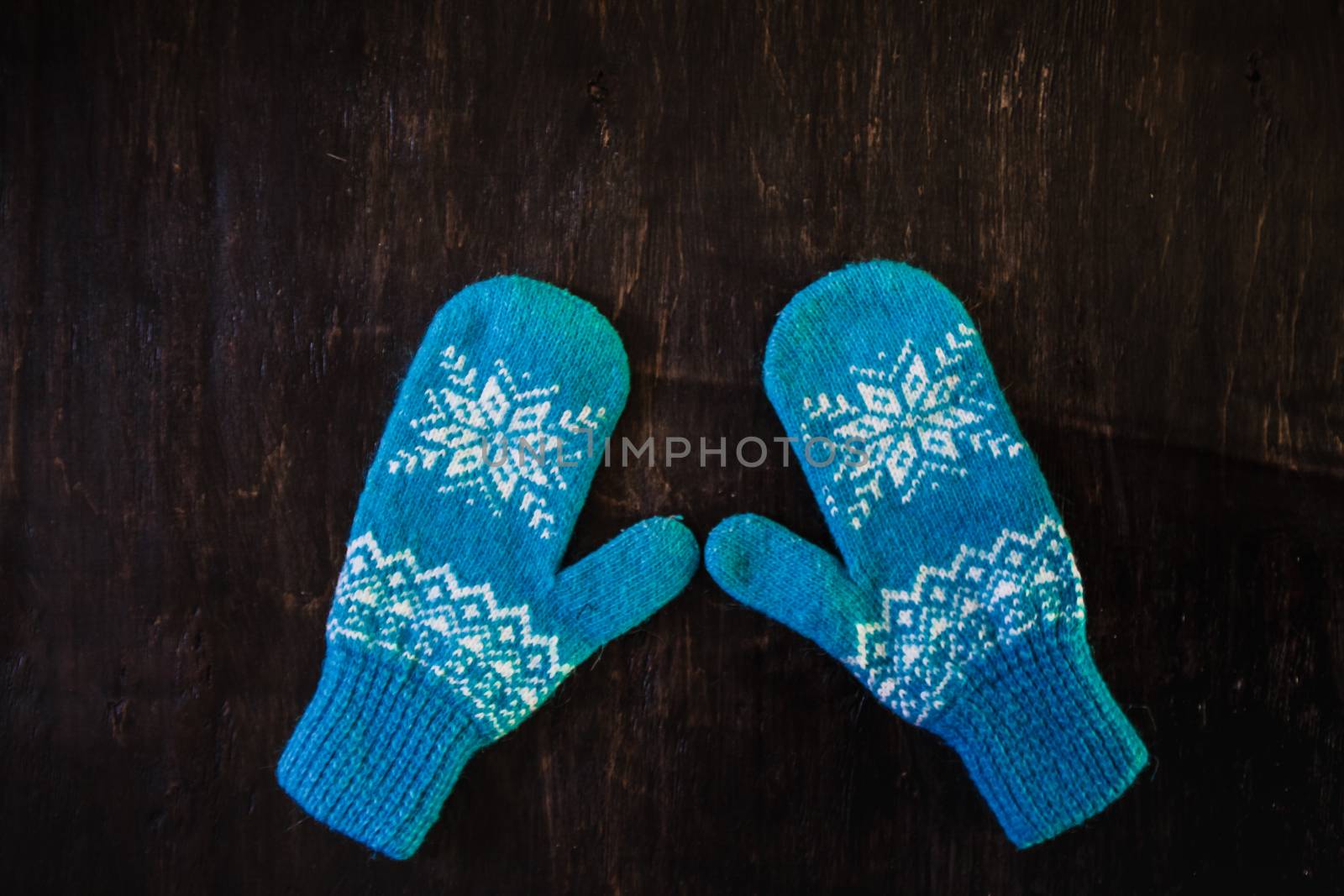a pair of blue knitted mittens on a dark blue-green-brown wooden vintage background, copy space.