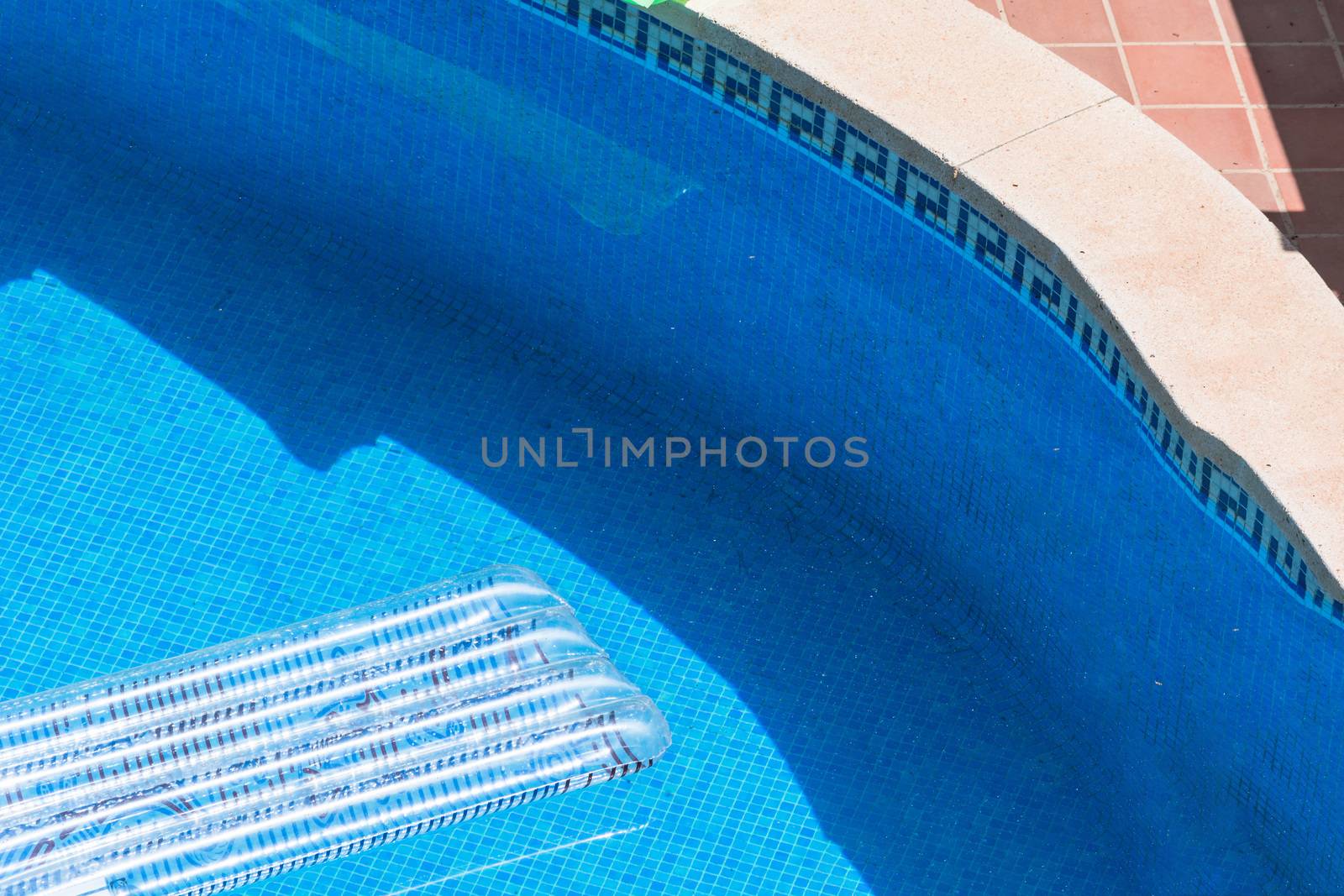 Transparent air mattress floats in a blue swimming pool.
