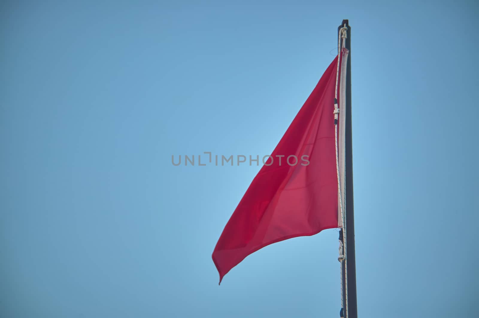 Pole with raised red flag, symbol of danger for bathers and navigators.