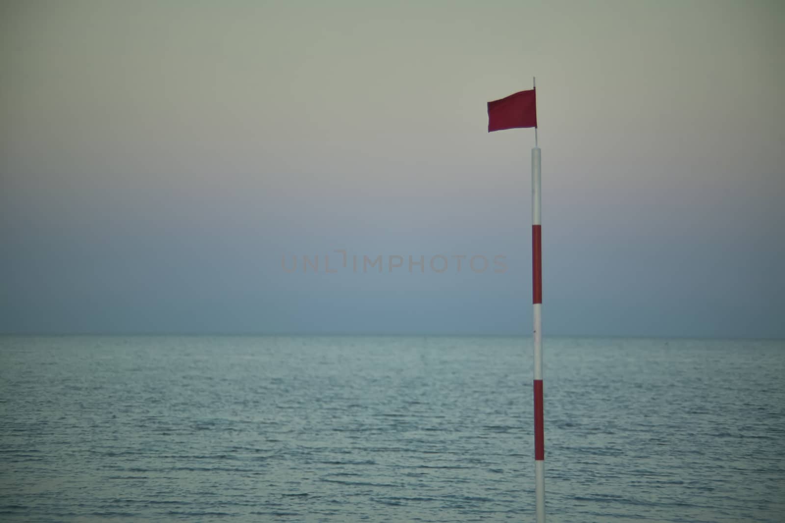 Pole with raised red flag, symbol of danger for bathers and navigators.