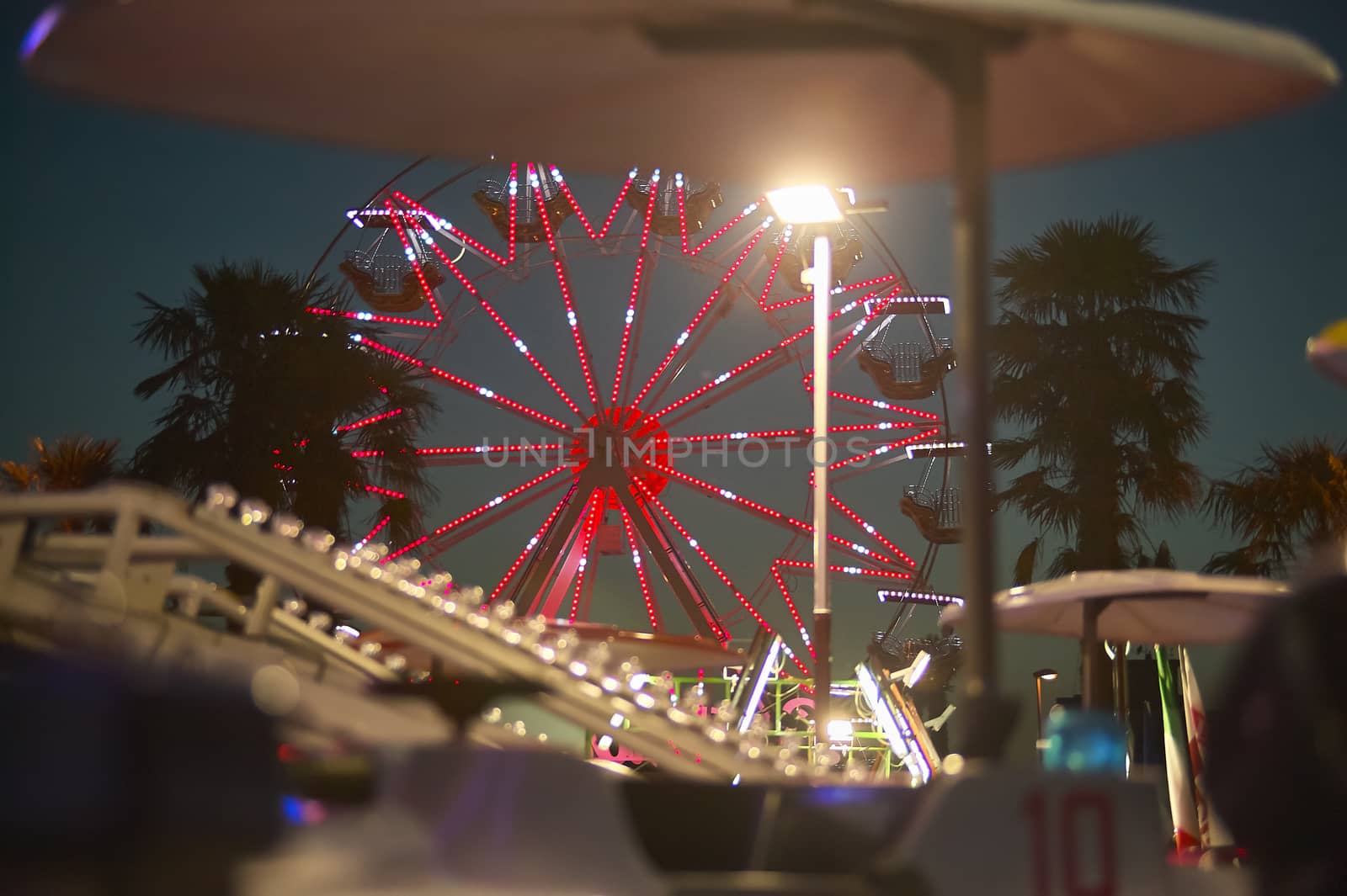 View of a panoramic wheel with the sunset behind, taken in a luna park in a seaside resort.