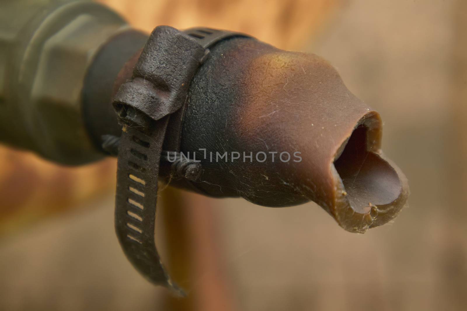 Detail of an old rusty iron clamp holding an old piece of time ruined pipe tied.