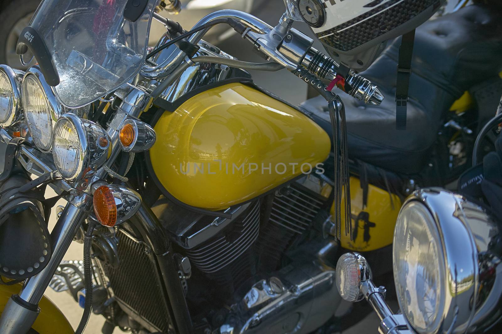 detail of the tank and engine of a yellow custom bike, motorcycle inserted in a rally with other bikes, of which sprouts some details.