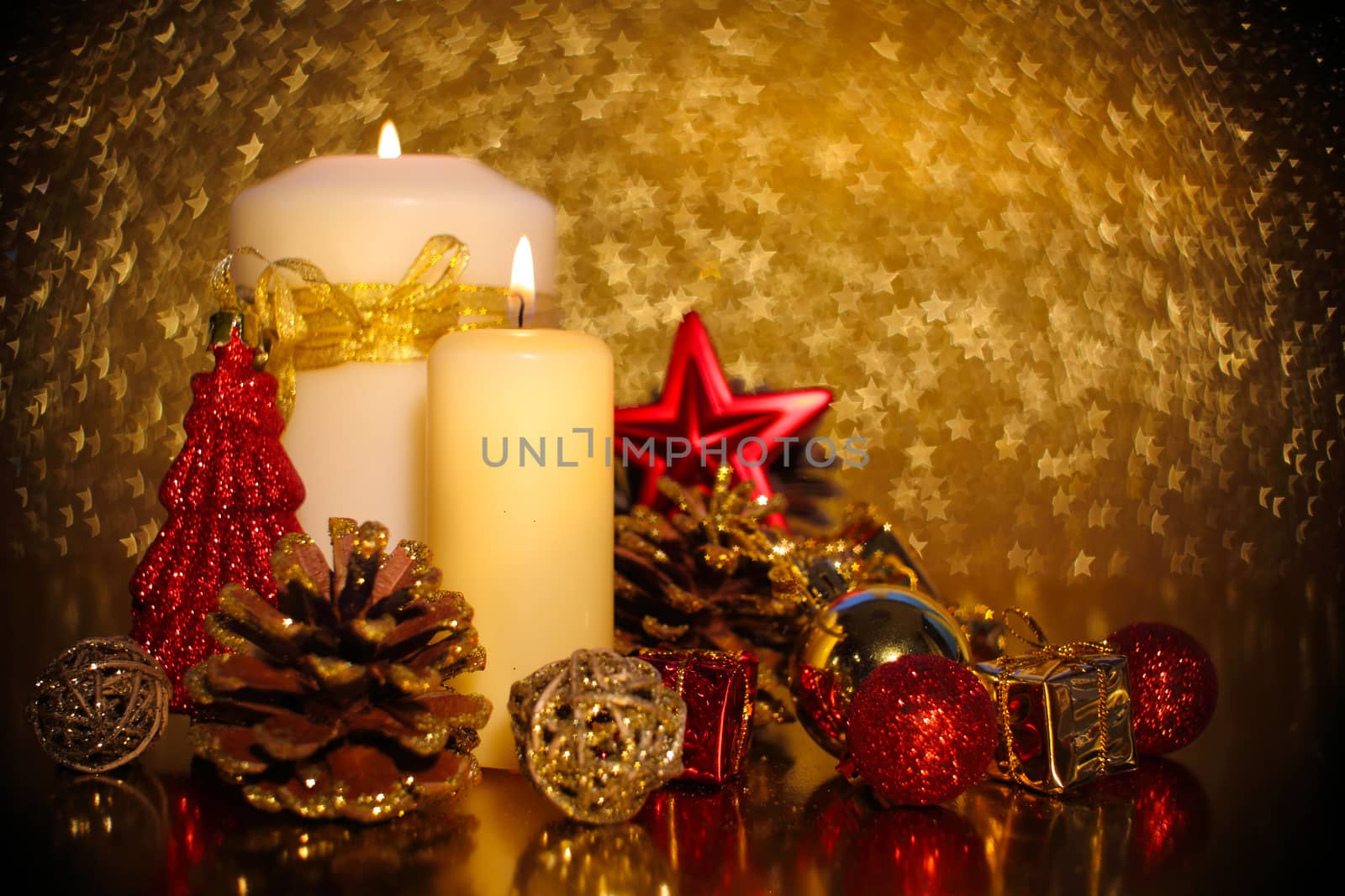 Christmas decoration of burning candle and decor over golden star bokeh background