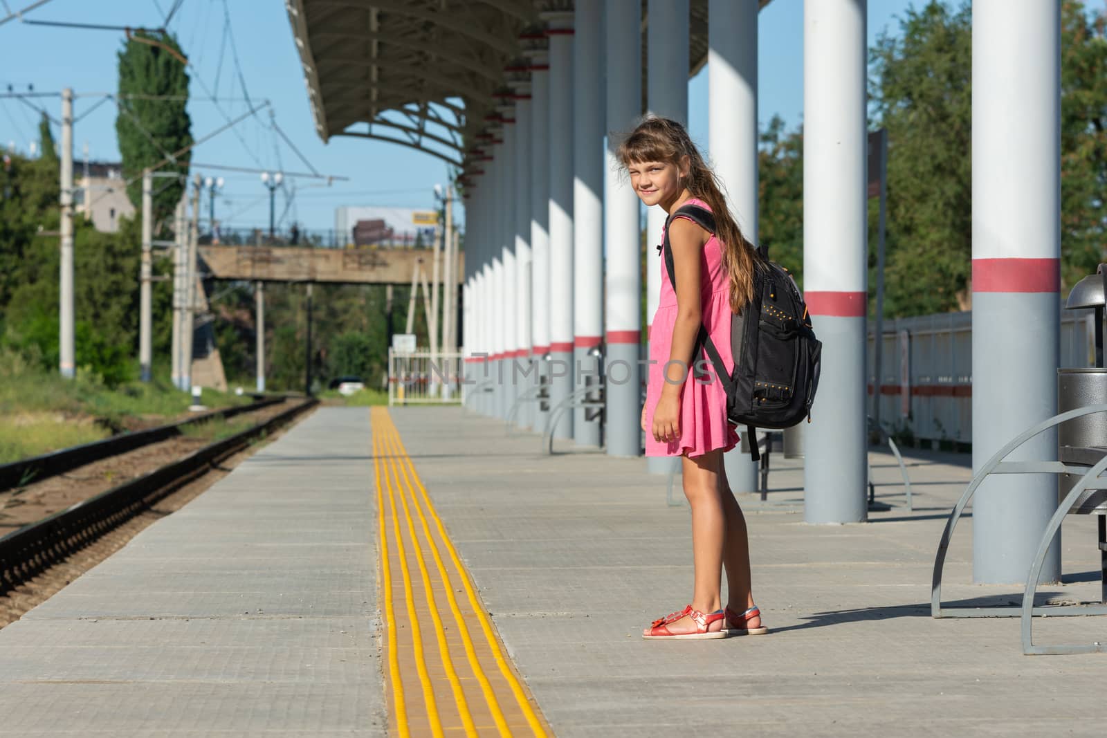 The eight-year-old girl on the platform of the railway station turned around and looked into the frame