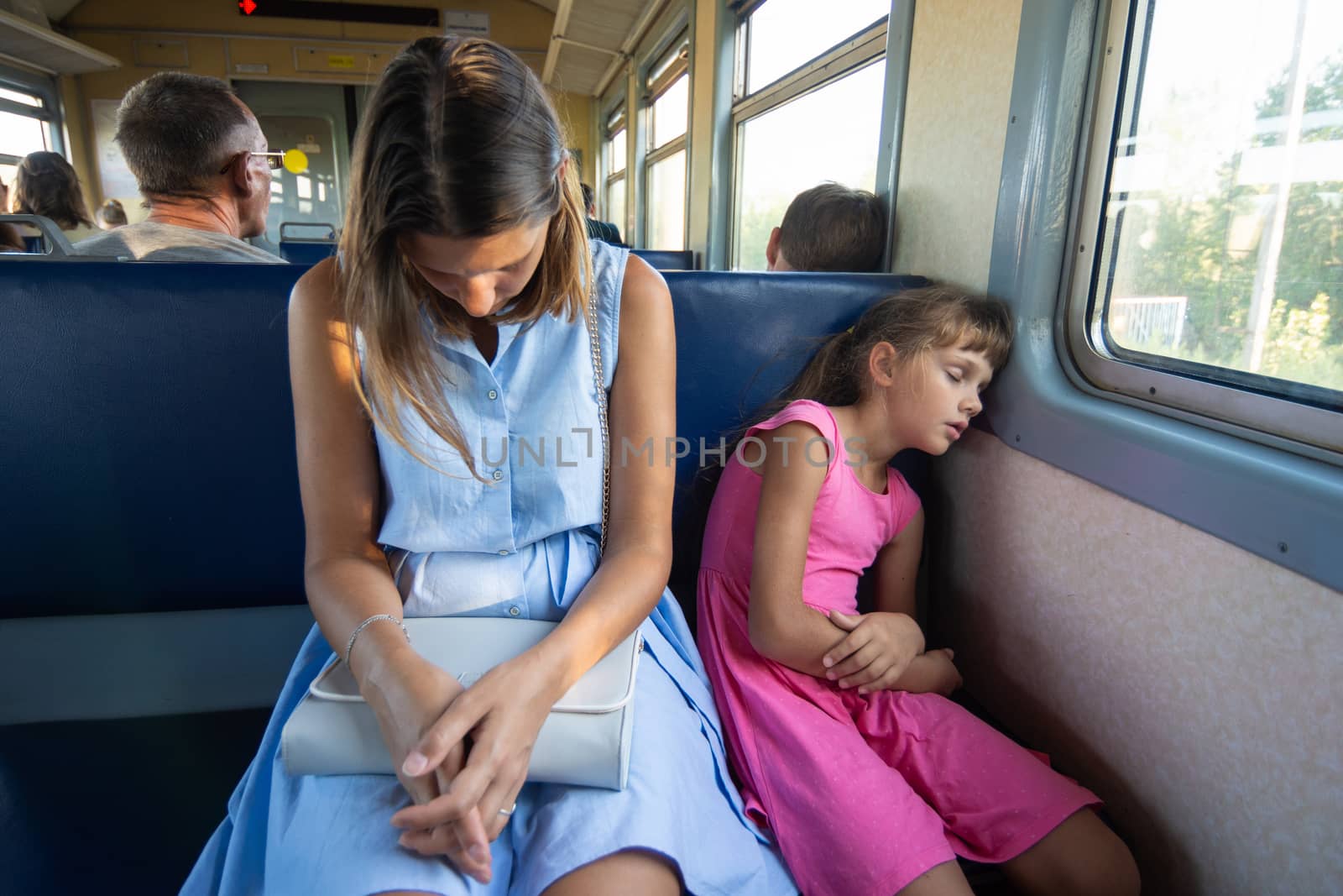 Tired mother and daughter sleep soundly in an electric train
