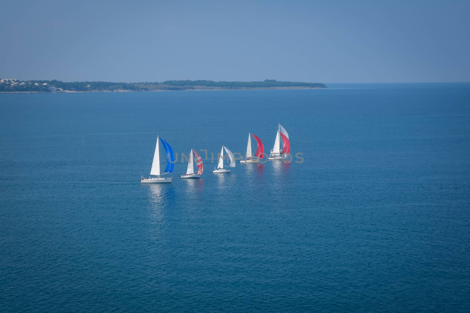 Sailing boats line up and compete in regatta off coast in Portoroz, Slovenia