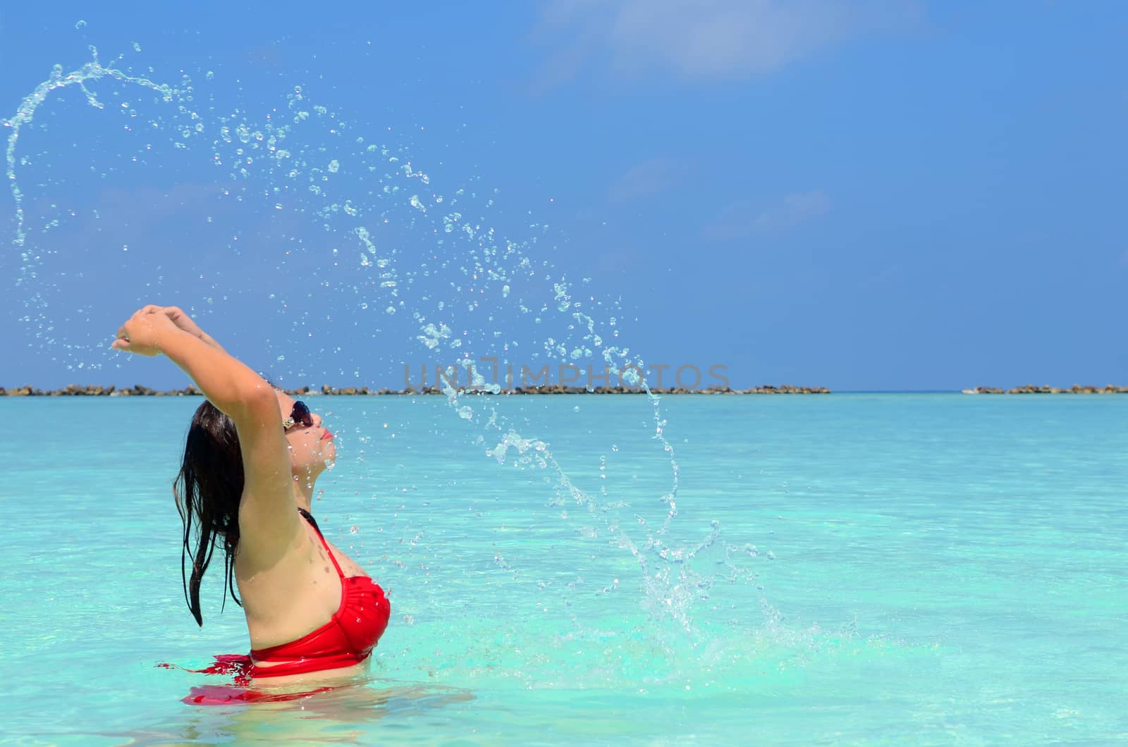 Woman swim and relax in the crystal-blue sea of tropical beach at  Maldives islands. Happy lifestyle concept. 