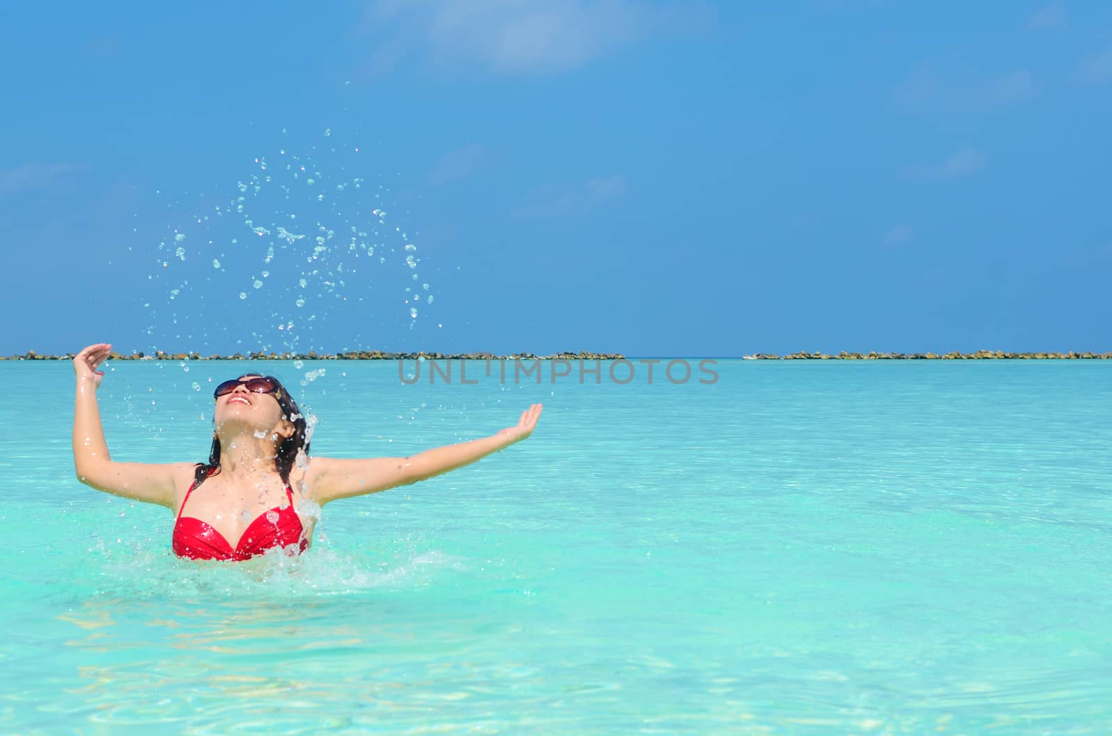 Woman swim and relax in the crystal-blue sea of tropical beach at  Maldives islands. Happy lifestyle concept. 