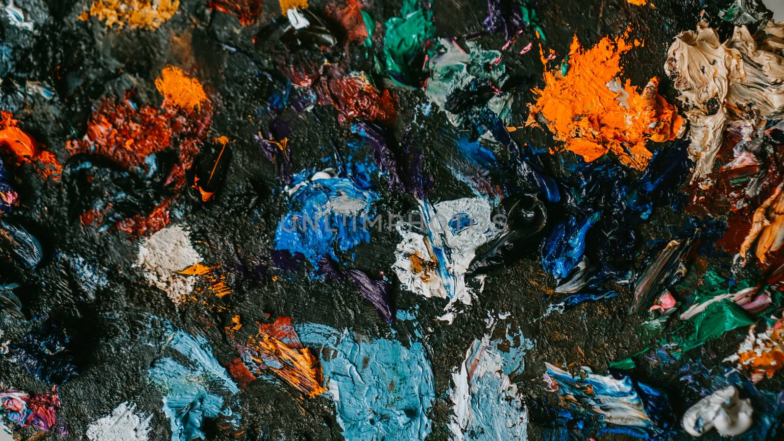 Background image of bright multi-colored oil-paint palette closeup