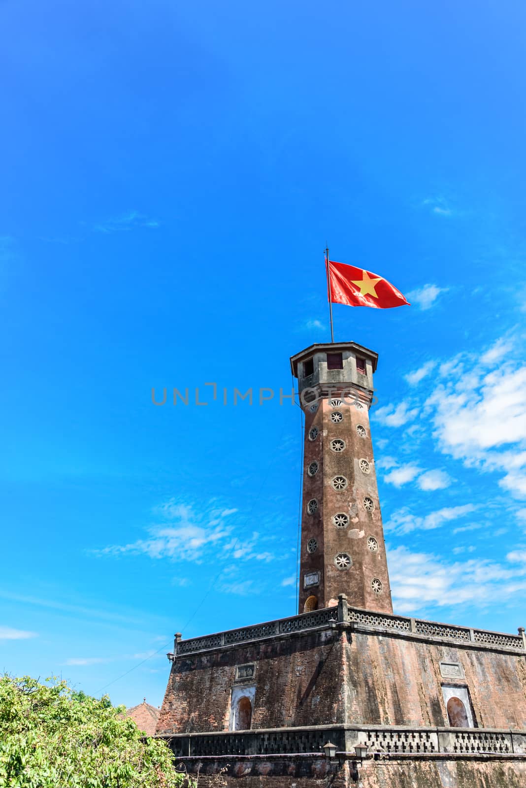 Close-up Hanoi flag tower with flying Vietnamese flag under cloud blue sky by trongnguyen