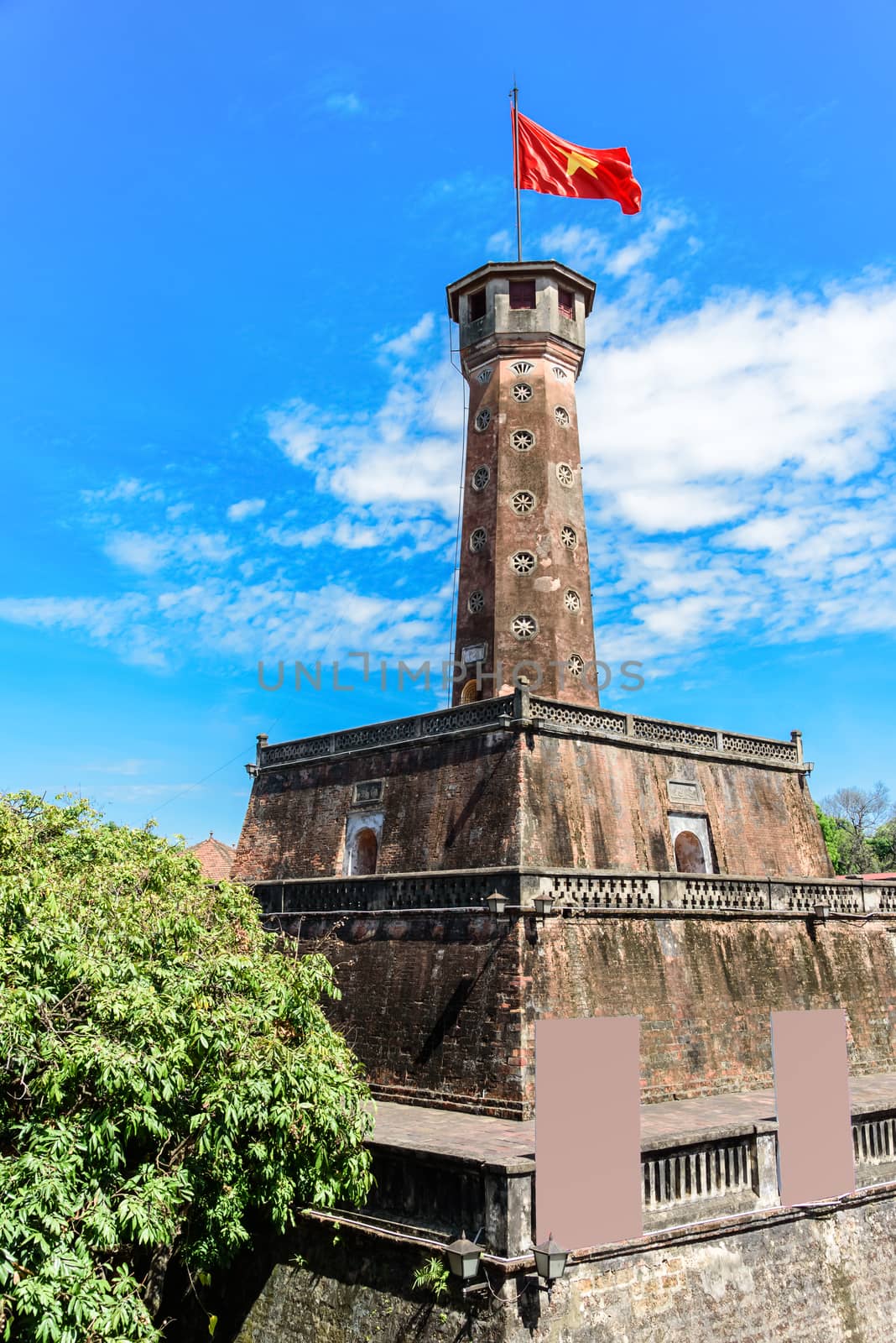 Close-up Hanoi flag tower with flying Vietnamese flag under cloud blue sky by trongnguyen