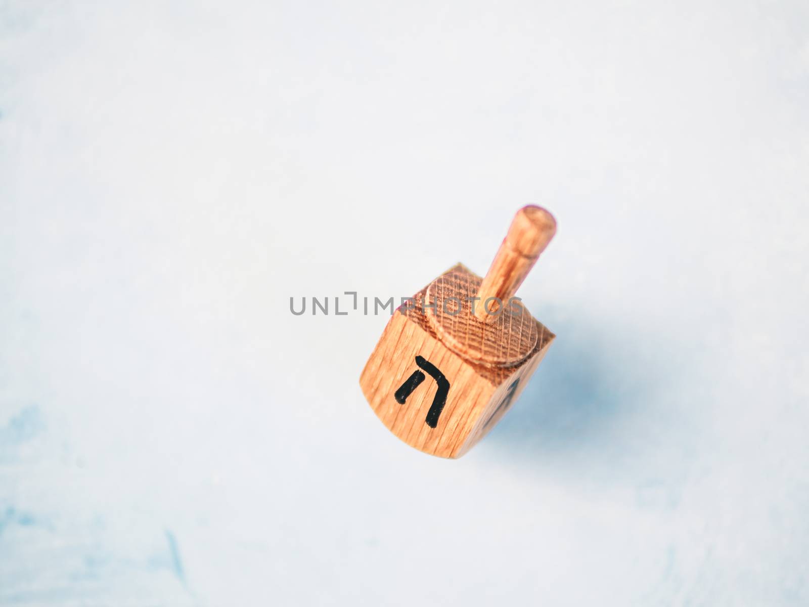 Jewish holiday Hanukkah concept and background. Hanukkah traditional spinnig dreidl or dredel on blue background. Dreidel with letter He of Hebrew alphabet. Copy space for text. Top view or flat lay.