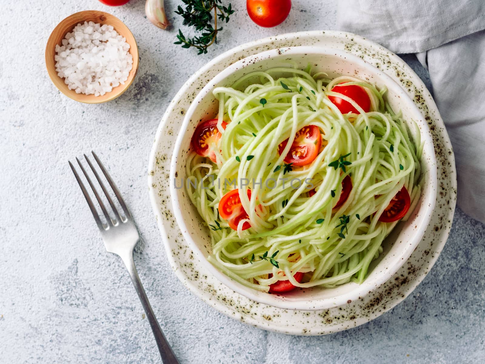 Zucchini noodles salad with cherry tomatoes. Vegetable noodles - green zoodles or courgette spaghetti salad ready-to-eat. Clean eating, raw vegetarian food concept. Copy space. Top view or flat lay.