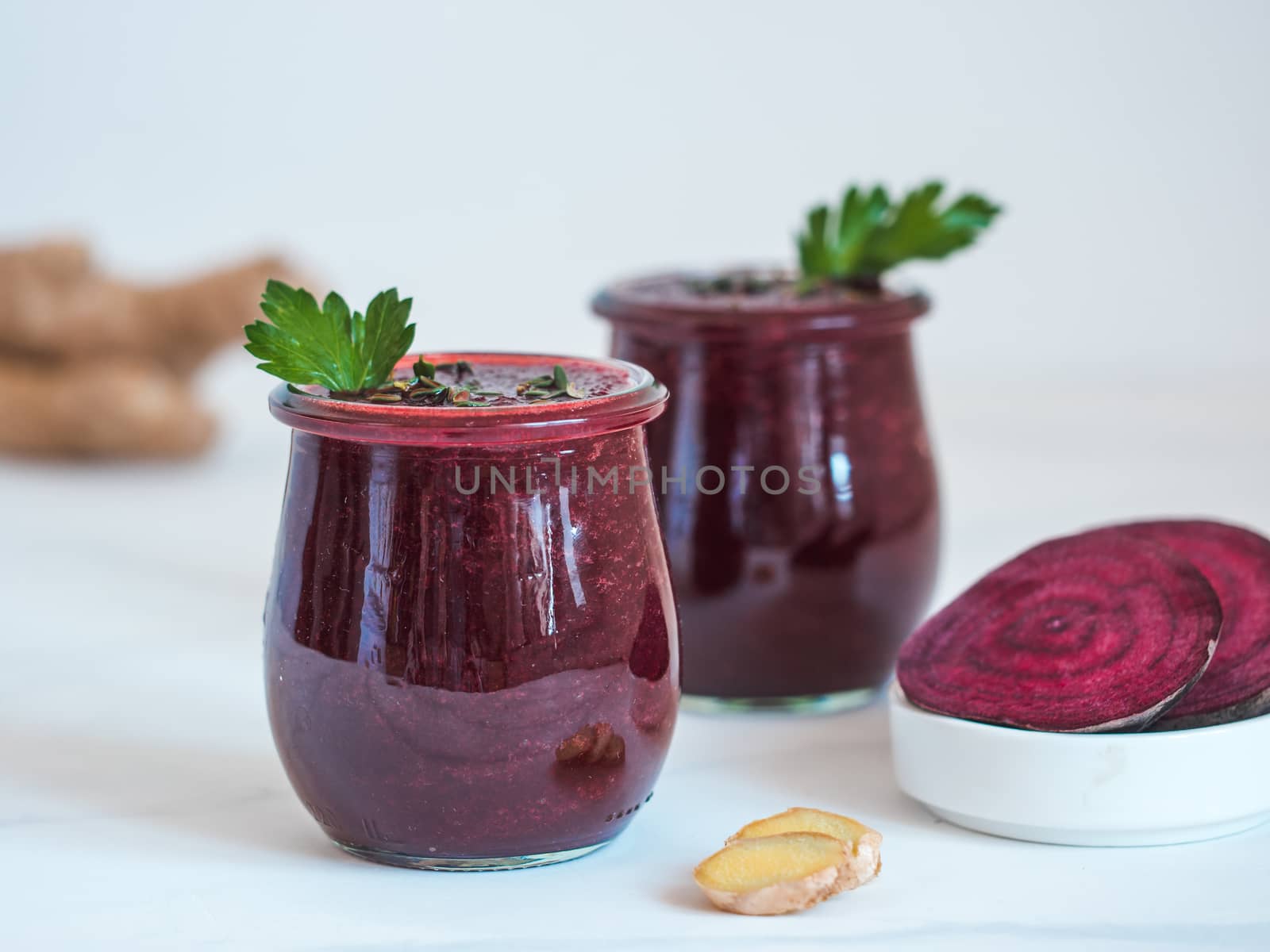 Fresh beetroot and ginger root smoothie. Beetroot smoothie in glass jar on white table. Shallow DOF. Copy space for text. Clean eating and detox concept, recipe idea.