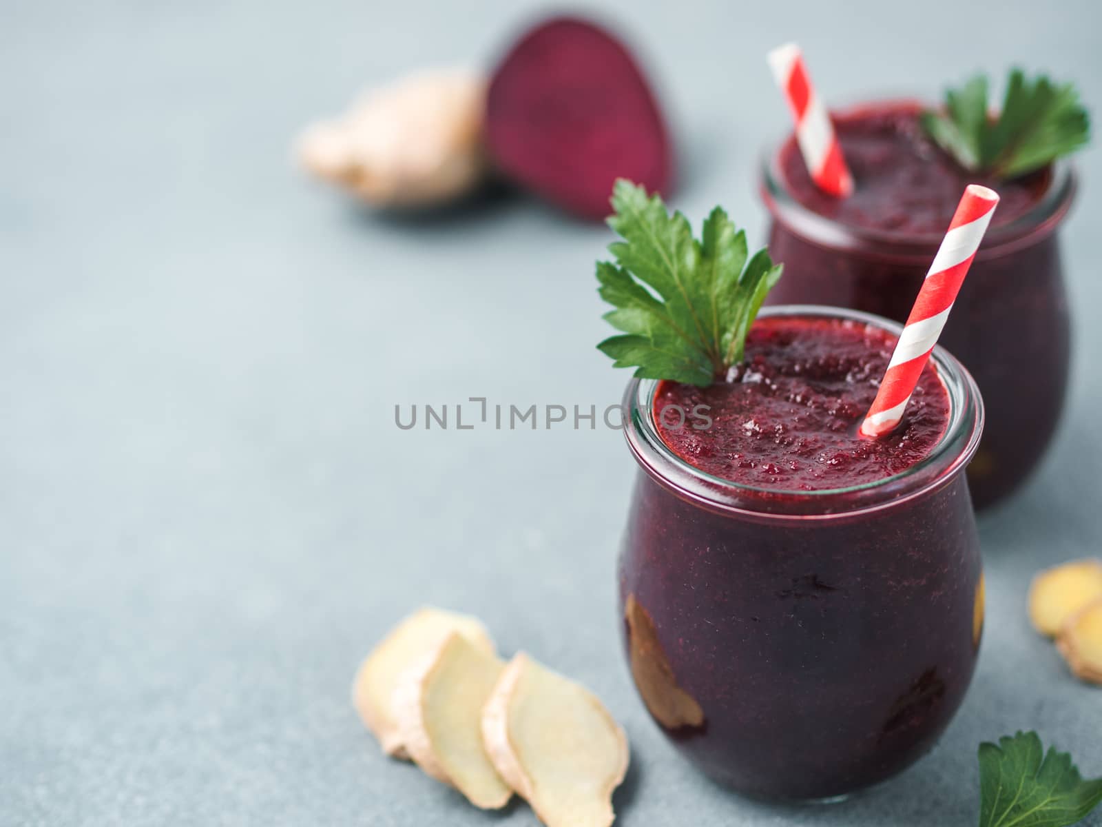 Fresh beetroot and ginger root smoothie. Beetroot smoothie in glass jar on gray table. Shallow DOF. Copy space for text. Clean eating and detox concept, recipe idea.