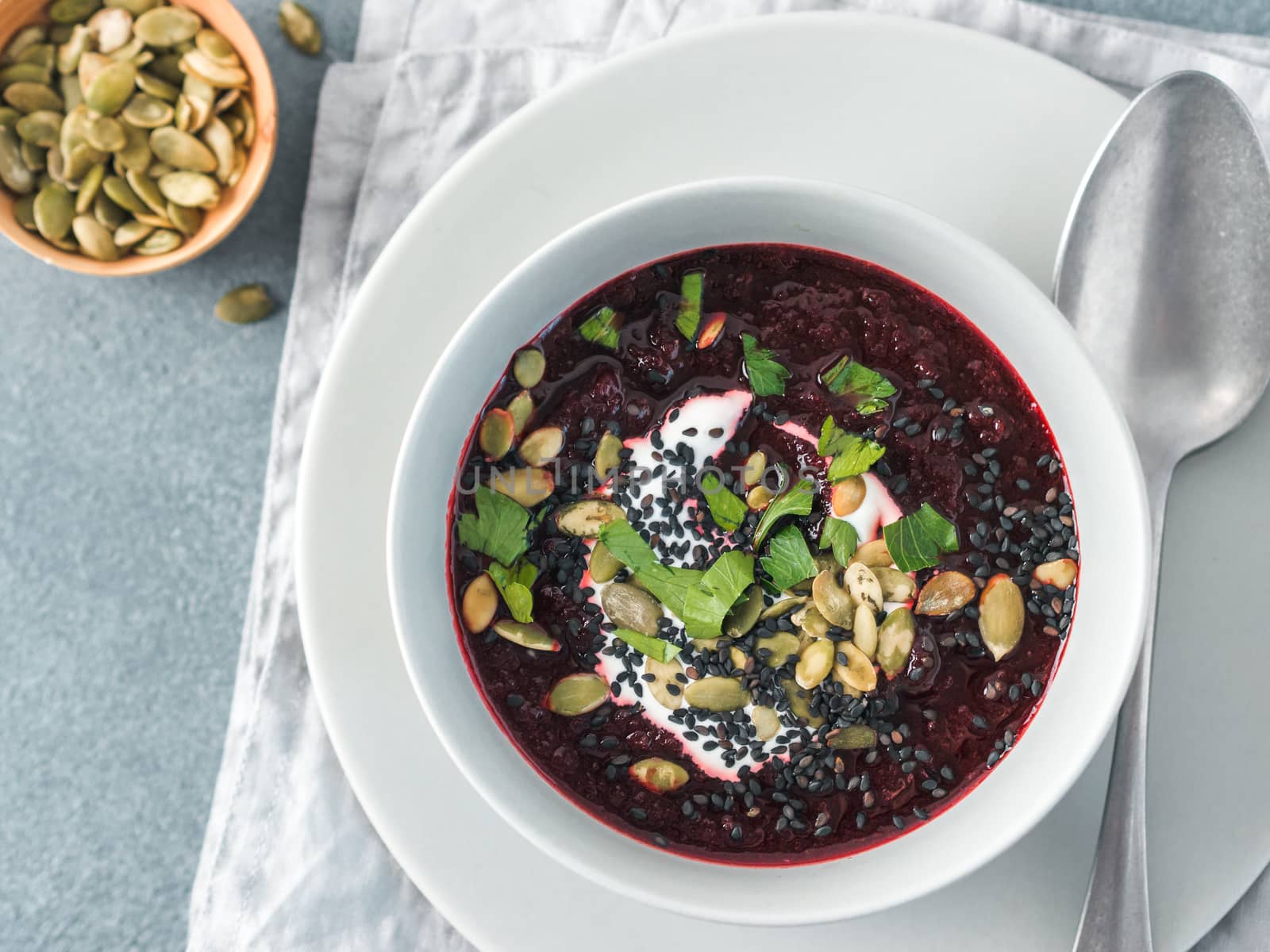 Ideas recipes for healthy soup - Beetroot and ginger soup puree. Clean eating, detox, vegetarian diet concept. Top view of plate with perfect beet soup, dressed pepitas, sesame and parsley. Copy space