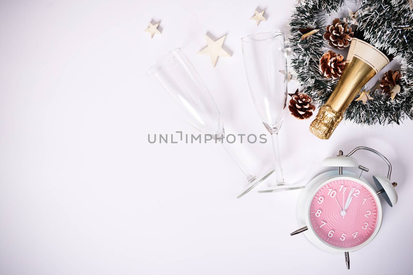 Christmas or New Year composition. Champagne bottle with two glasses, decoration and a clock showing almost midnight, on white background. Christmas, New Year concept. Flat lay,  top view.