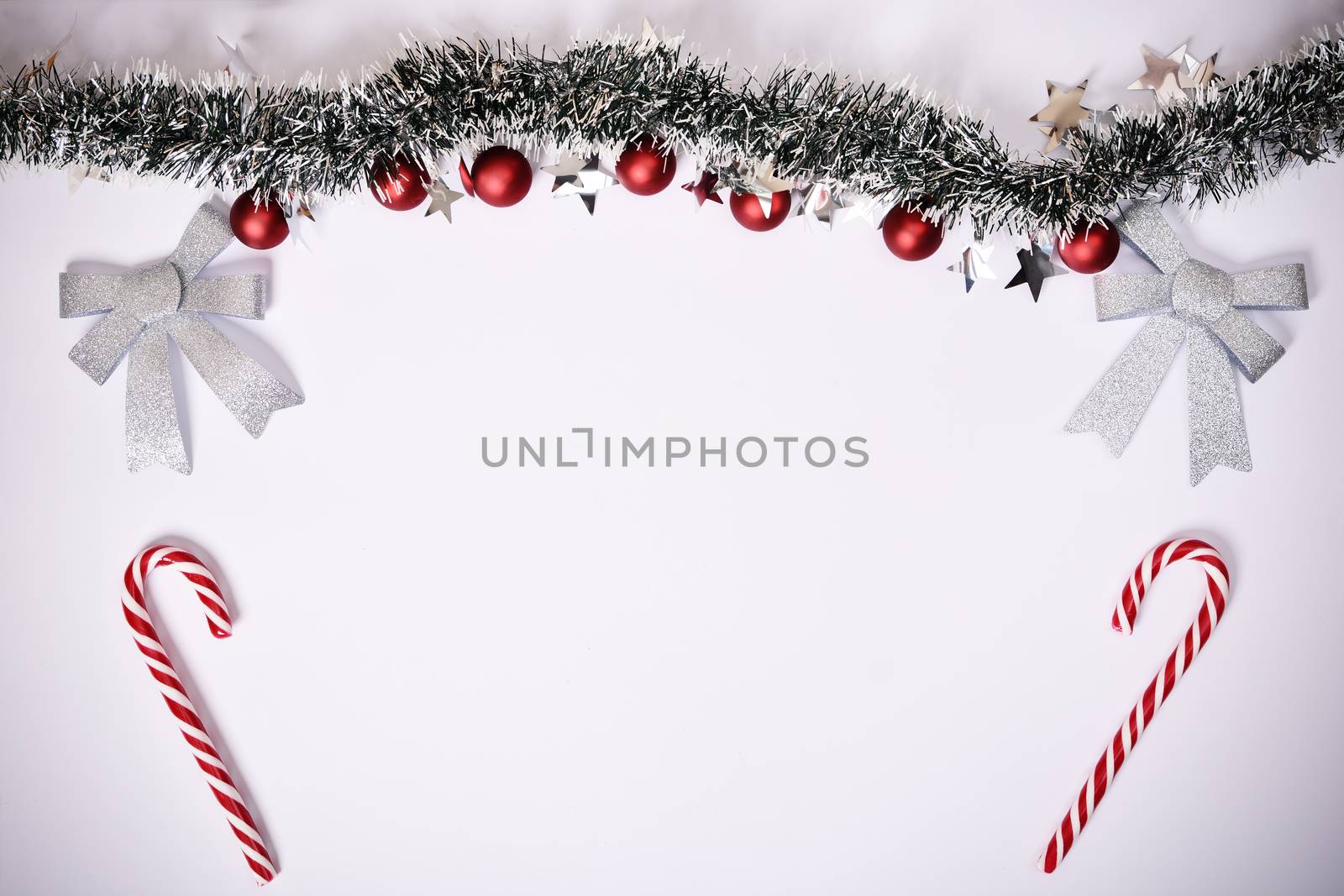 Christmas composition. Garland with red balls, stars, glittery bows and candy canes on white background. Christmas, winter, new year concept. Flat lay, top view, copy space.