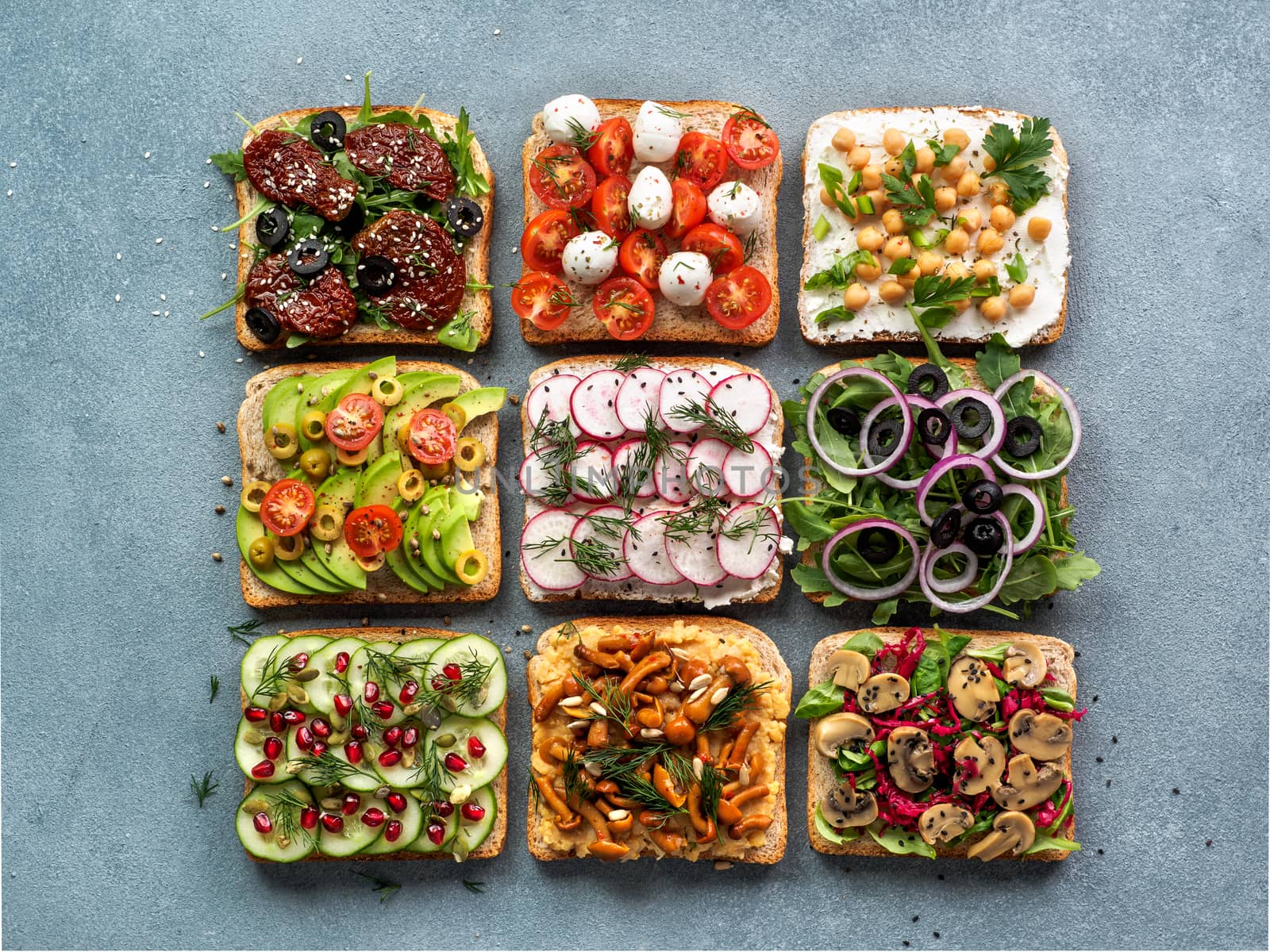 Assortment vegan sandwiches on gray stone background. Set different vegetarian smorrebrod. Top view or flat lay.