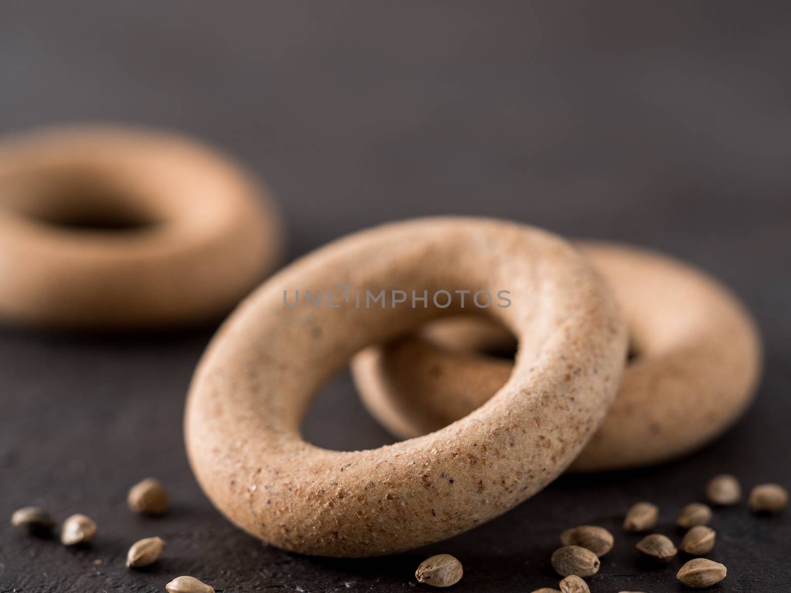 Ring-shaped cracknel with whole grain hemp seed flour and hemp seeds on black background. ring-shaped cracknel close up. Copy space