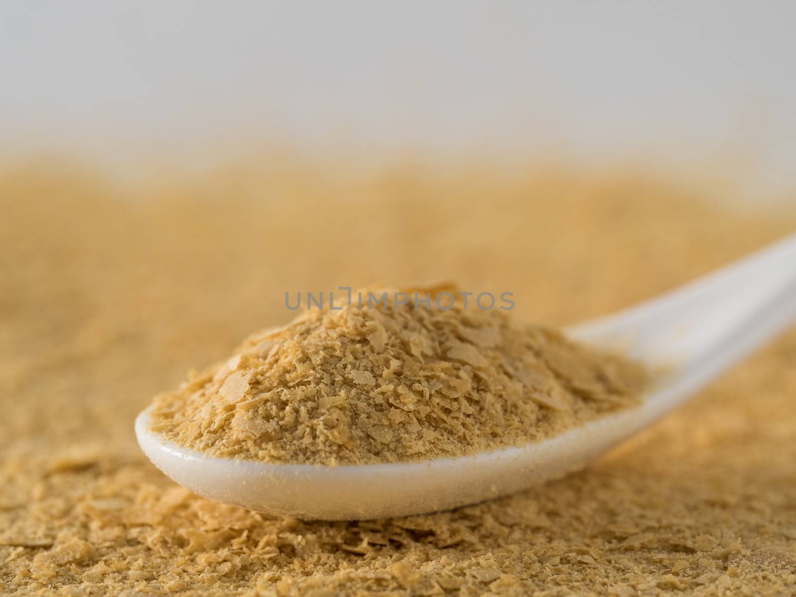 Nutritional yeast background. Nutritional inactive yeast in white spoon. Copy space. Nutritional yeast is vegetarian superfood with cheese flavor, for healthy diet