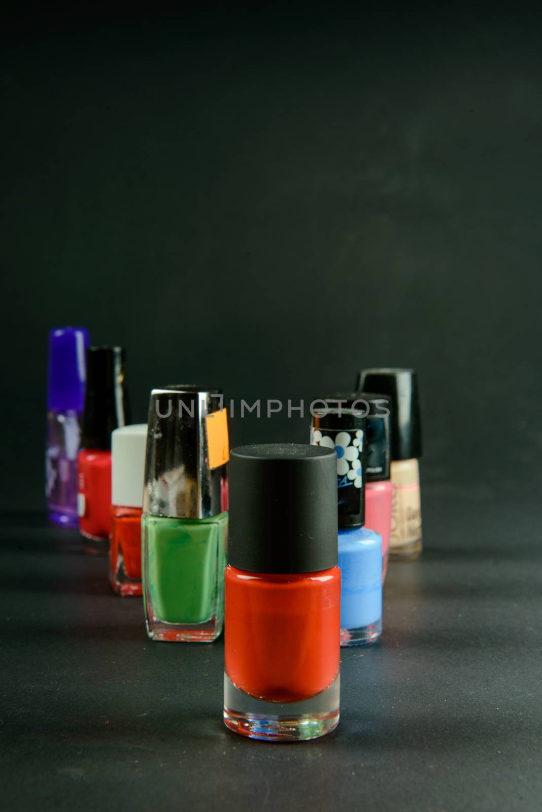 a photograph of coloured nail polish bottles on dark background