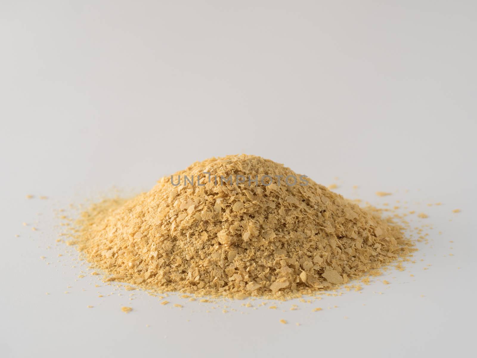 Nutritional yeast heap on white background. Nutritional inactive yeast. Copy space. Nutritional yeast is vegetarian superfood with cheese flavor, for healthy diet