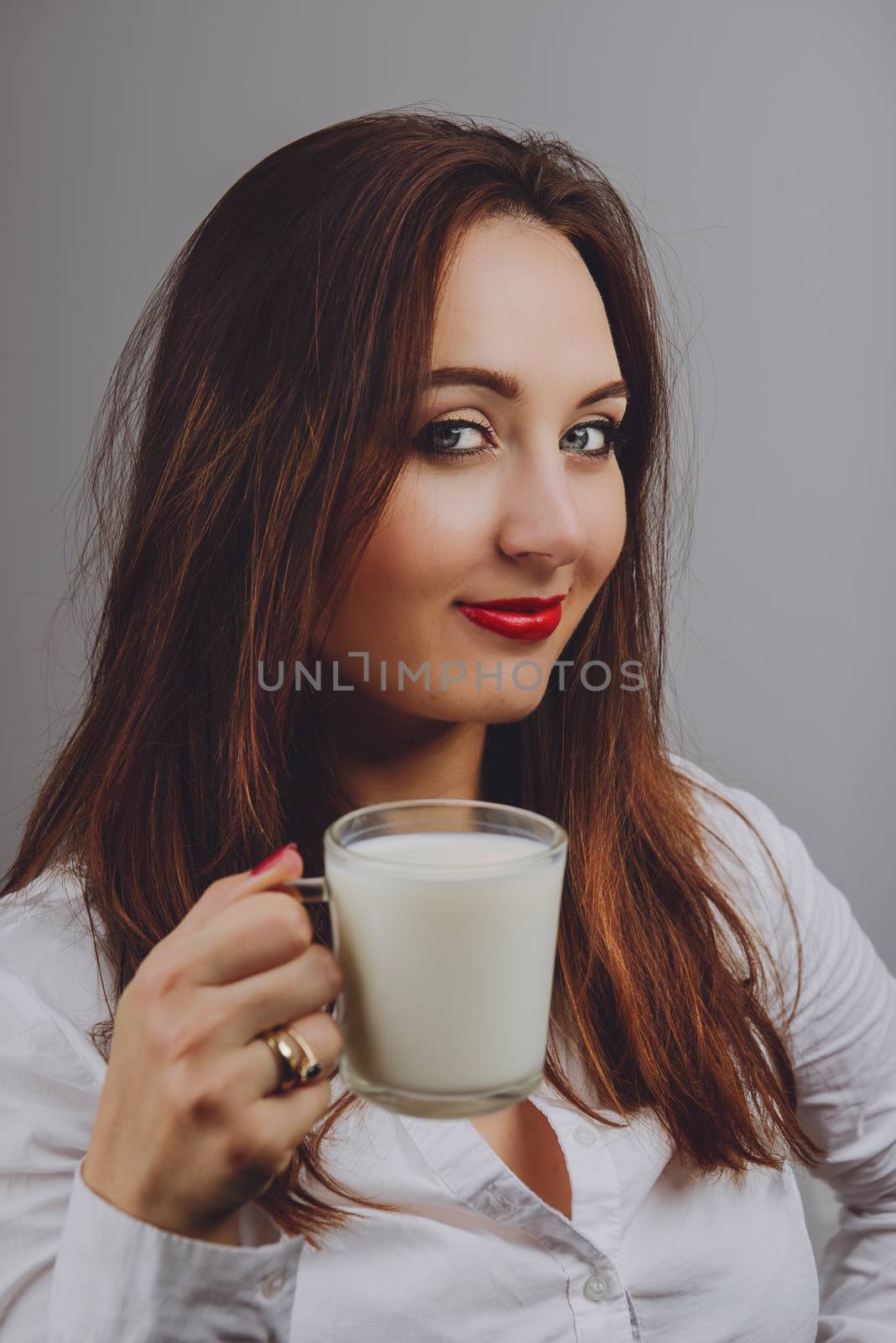 Cheerful girl holding milk mug in hand. Milk is a source of calcium