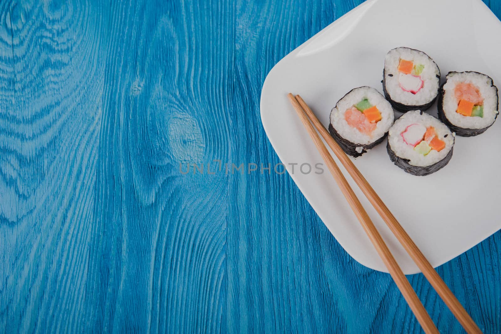Appetizing tasty Japan rolls on a plate isolated on blue wooden background