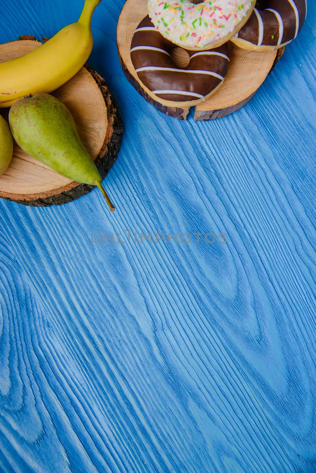 fruits lying on the table againts donuts, make a choice