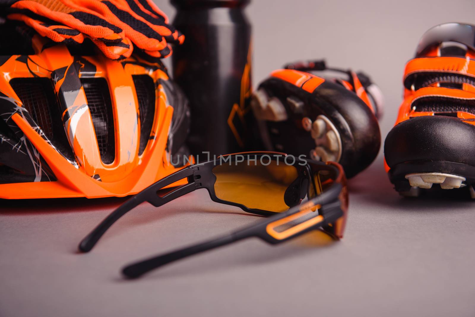 Helmet, gloves, shoes and water bottle - bicycle accessories. Orange color