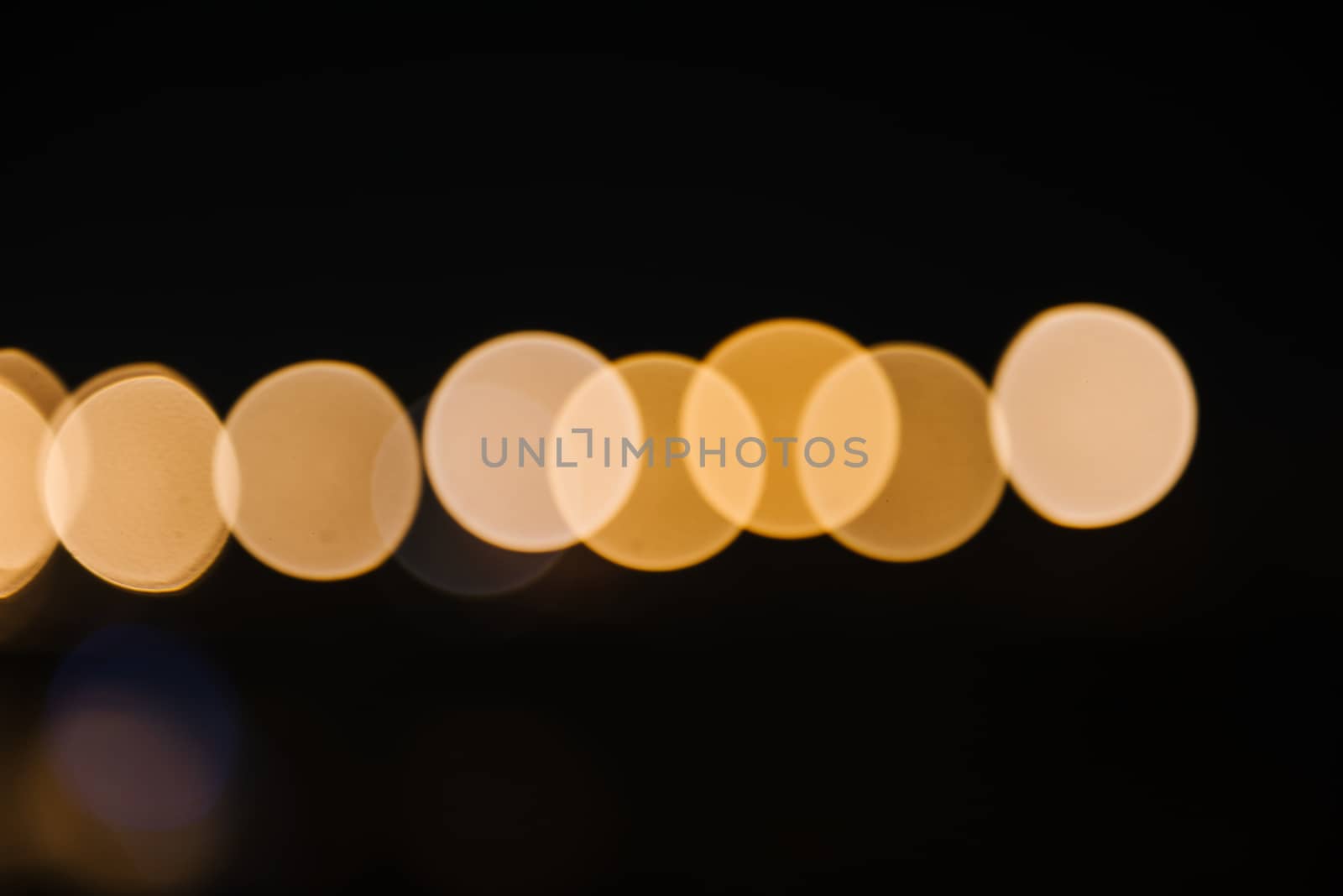Colorful city lights with bokeh effect reflected over sea background at dusk.