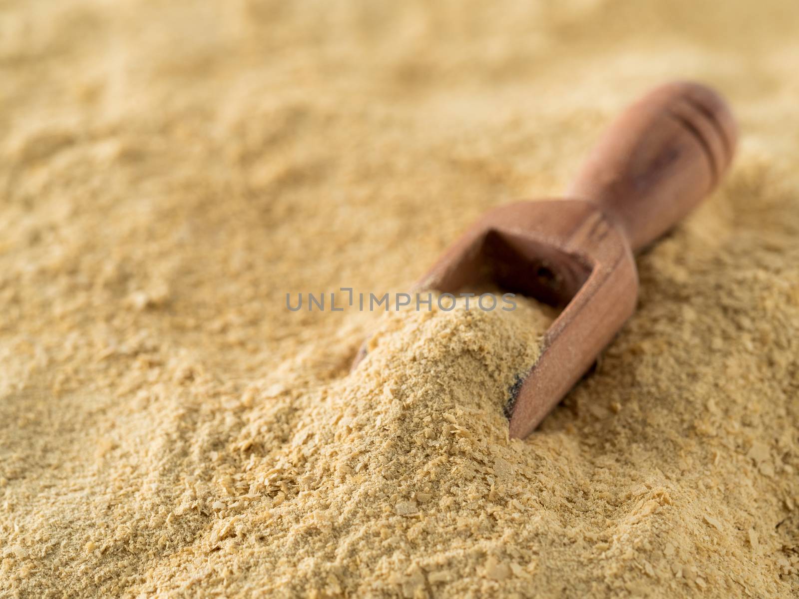 Nutritional yeast background. Nutritional inactive yeast with small wooden scoop. Copy space. Nutritional yeast is vegetarian superfood with cheese flavor, for healthy diet