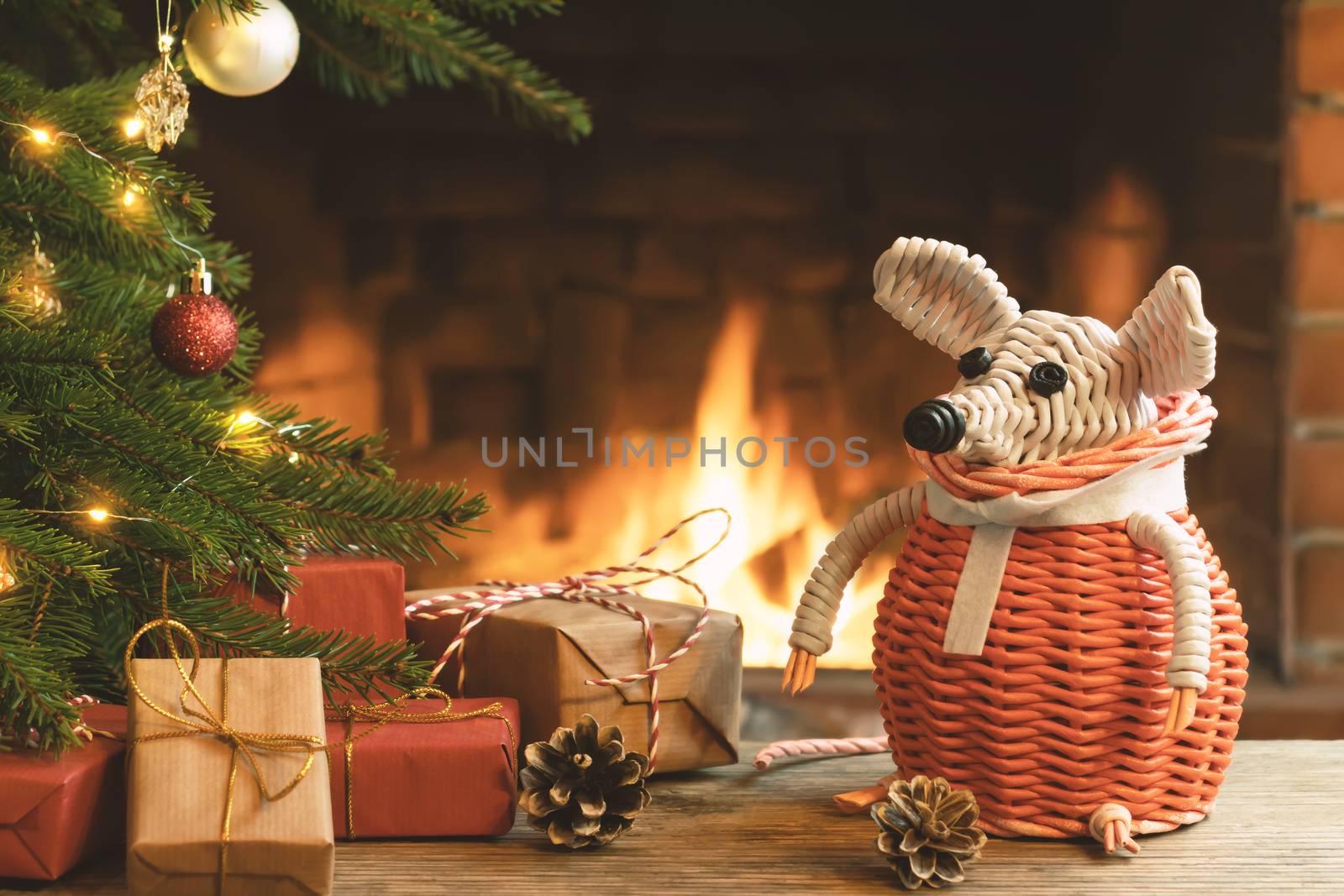 Christmas composition - a wicker white mouse - symbol of 2020 according to Chinese horoscope next to gifts under Christmas tree in room by fireplace. by galsand