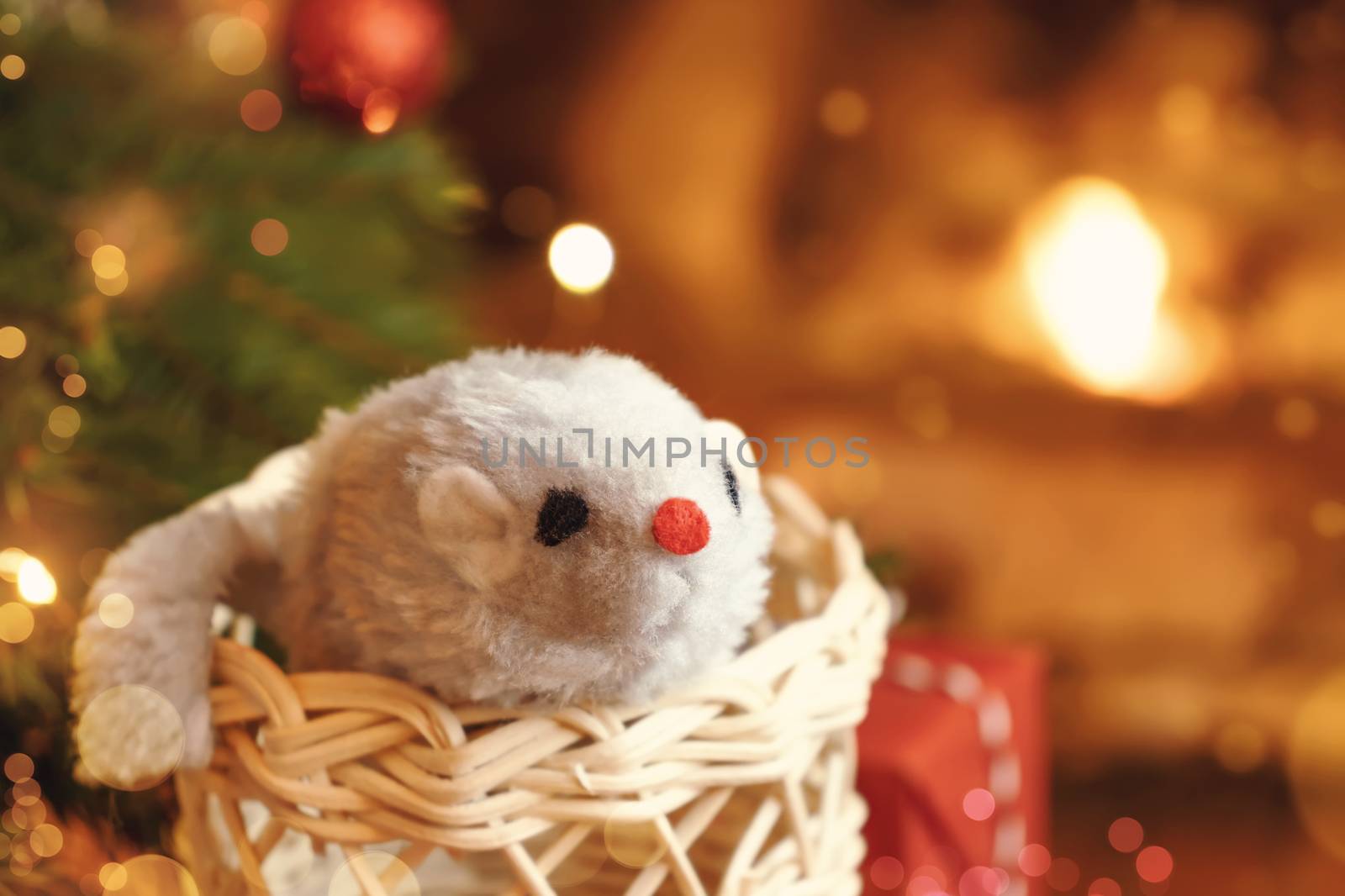 Christmas composition - mouse is symbol of 2020 according to Chinese horoscope in wicker boot near Christmas tree in room by fireplace.