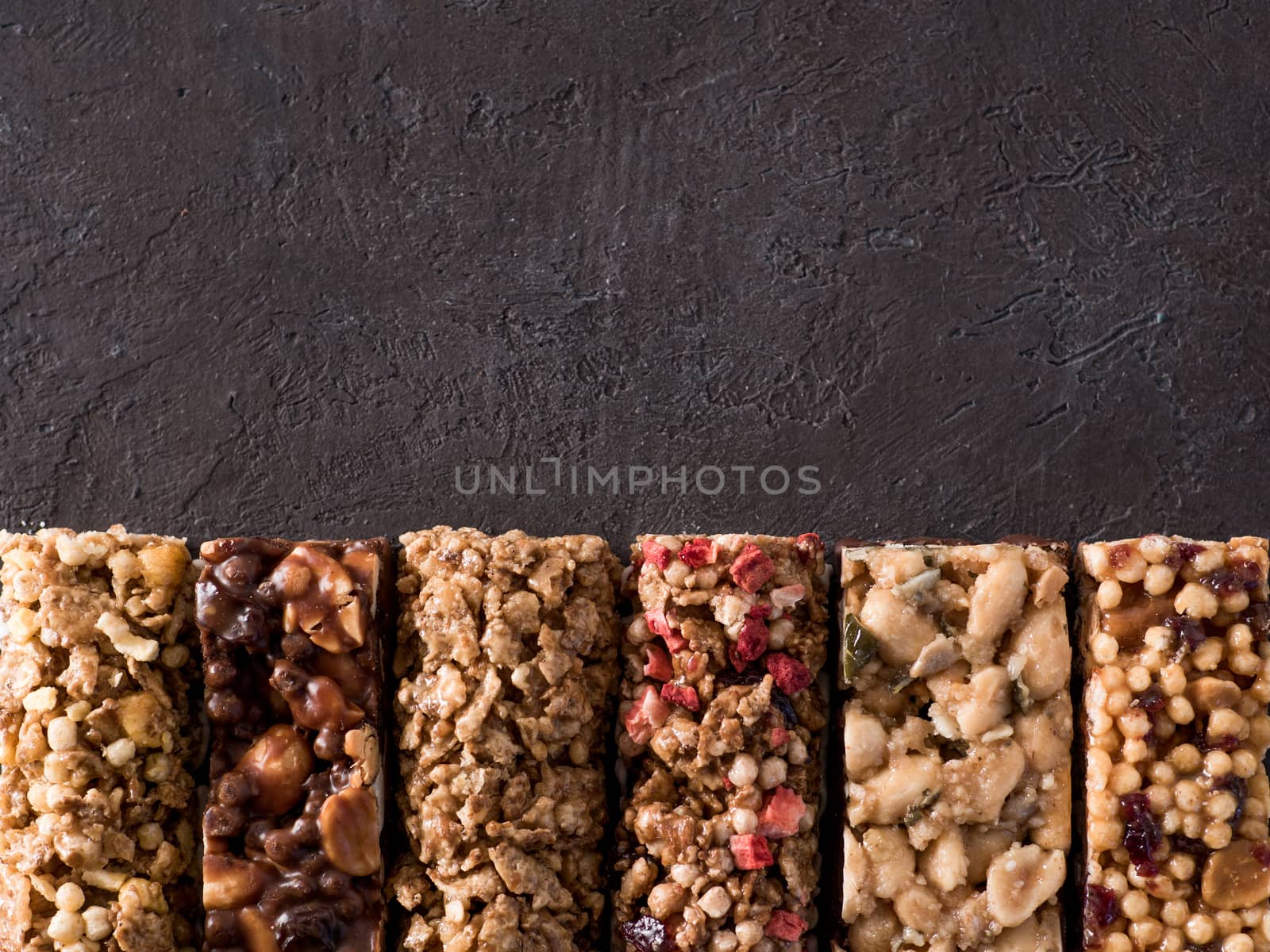 Granola bar with copy space. Set of different granola bars on black background. Shallow DOF. Top view or flat lay.