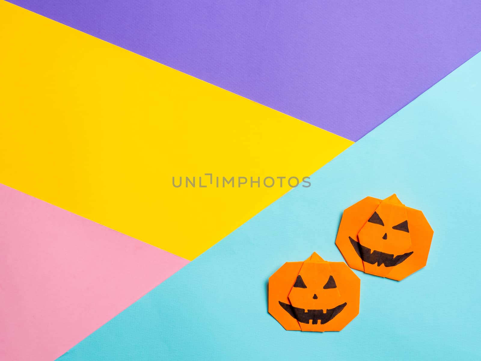 Halloween concept. Paper origami pumpkin on colorful background. Simple idea for halloween - easy made paper pumpkins on multicolor background. Copy space for text.