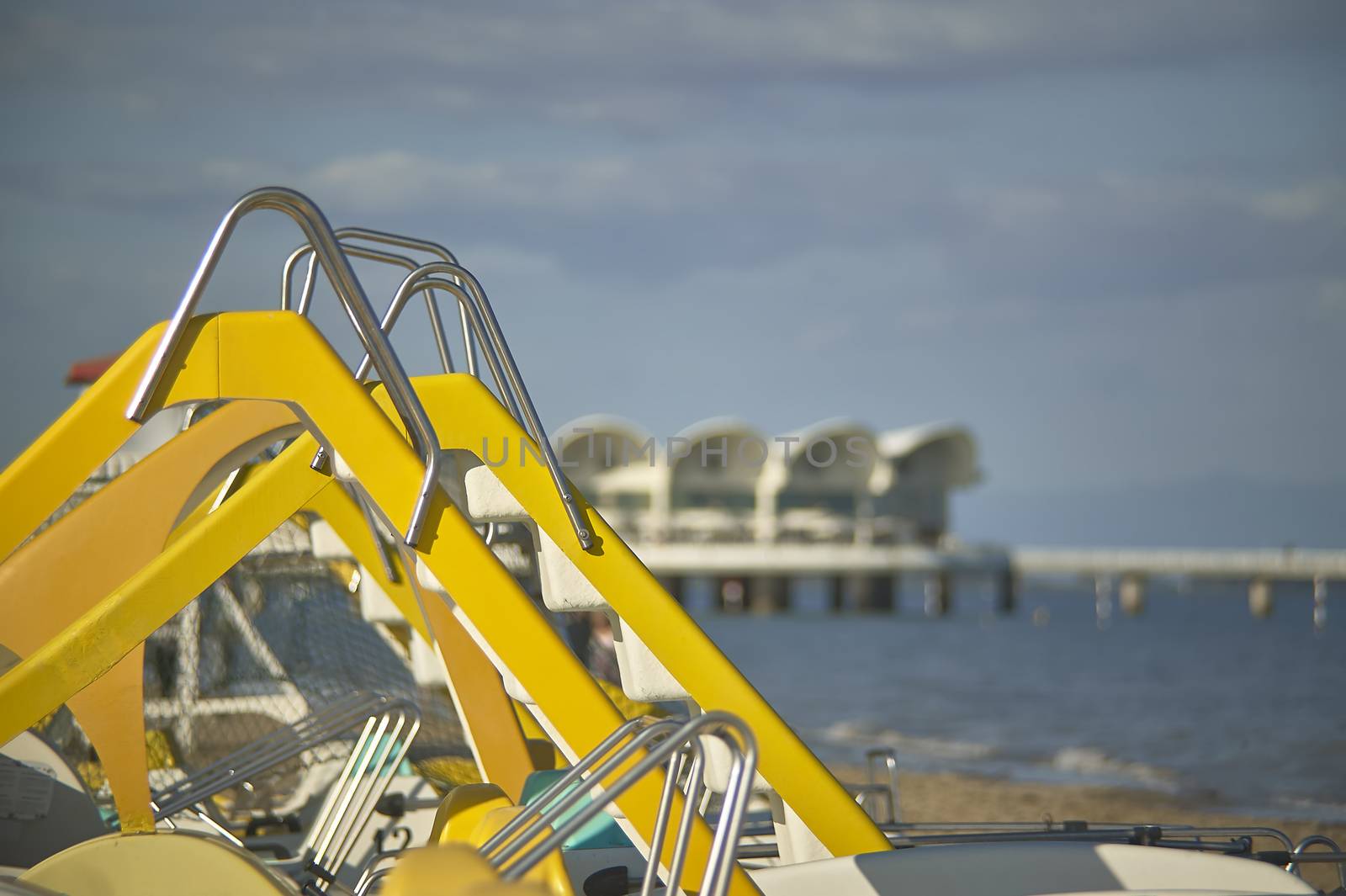 detail of the scoop of some pedal boats rented for tourists in the seaside resort, with the blurry beach background.