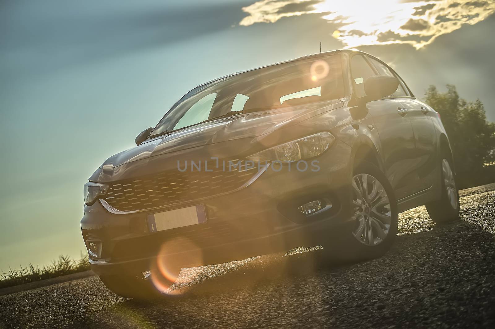 Modern car shot from below with wide angle behind with sunset and a beautiful light that contrasts. Light flare on the lens.