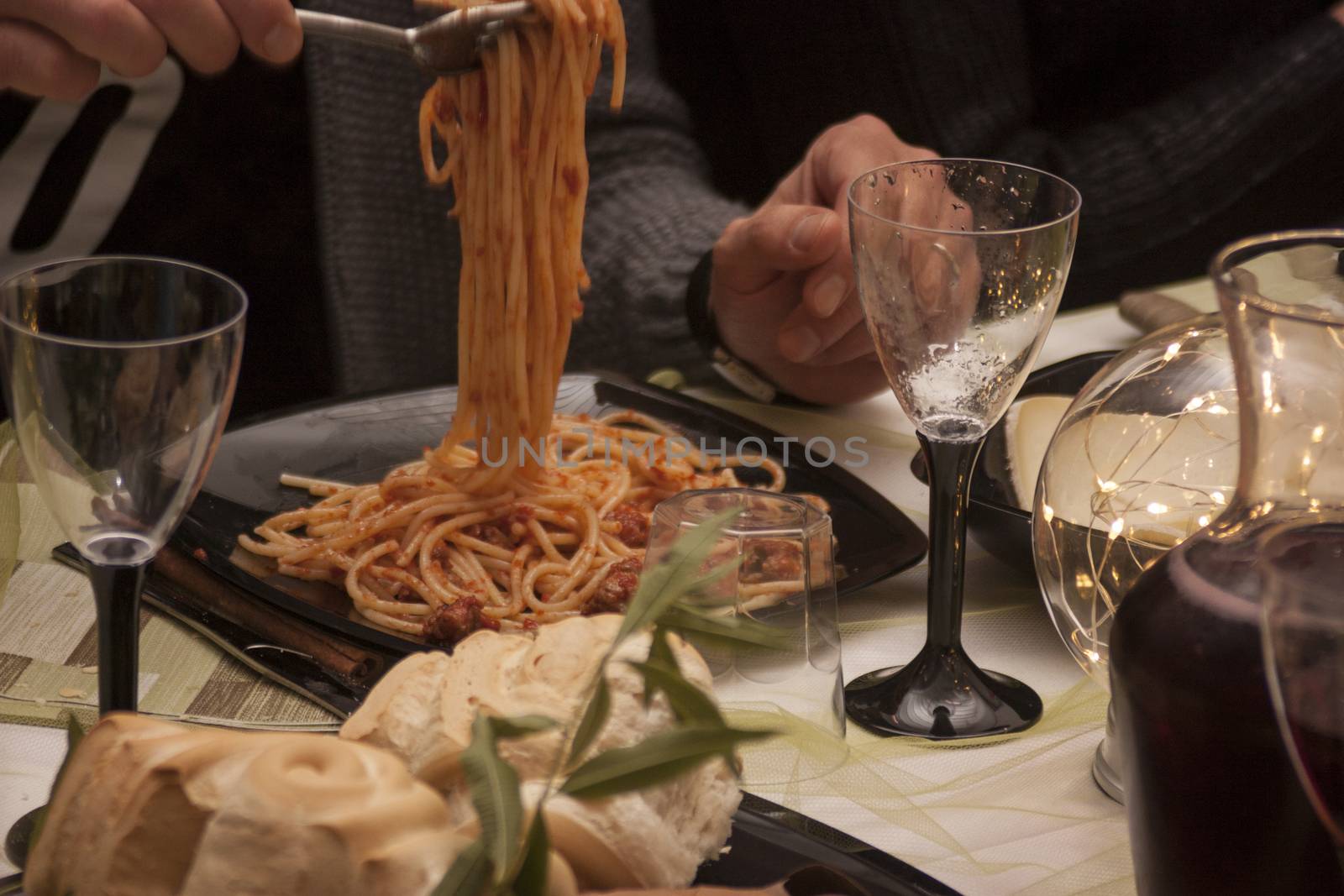 hand holding fork and handing a bite of spaghetti to ragu on a table during a lunch