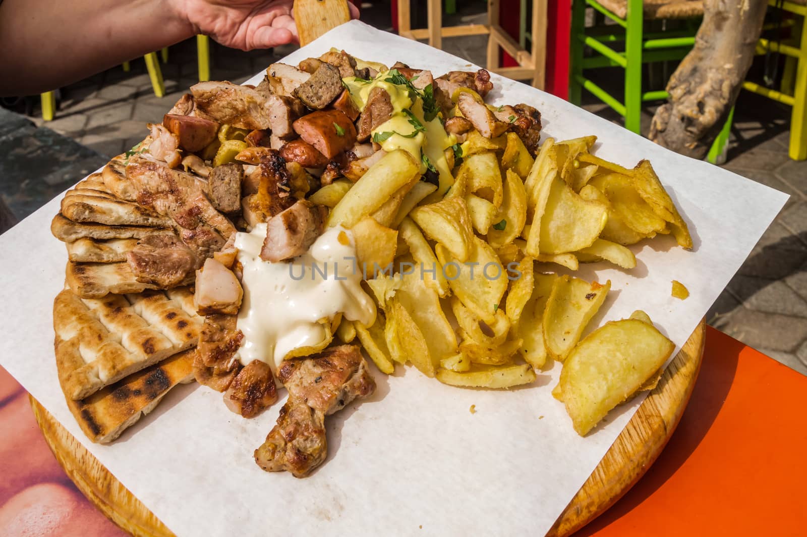 Plate of grilled meat with fries and pita bread on a wooden board